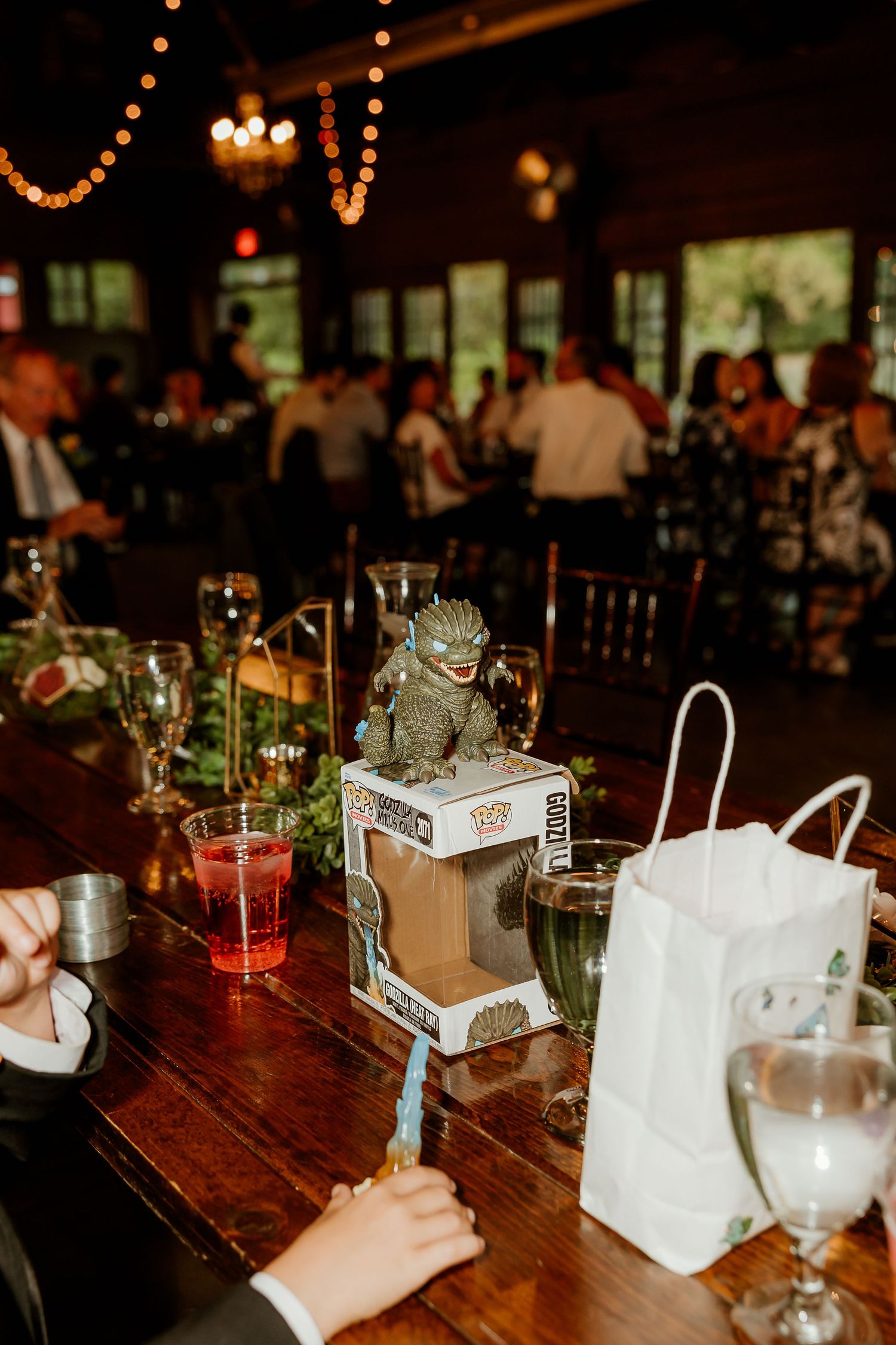Godzilla Funko Pop figure displayed as a wedding reception table centerpiece on a rustic wooden table.
