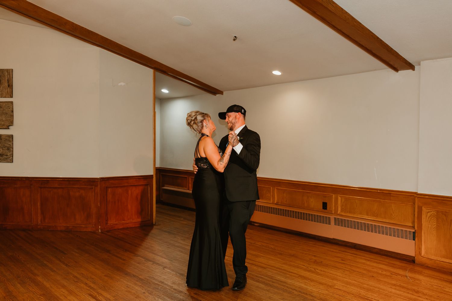 Couple dancing elegantly in formal attire in a wood-paneled ballroom during a special event.