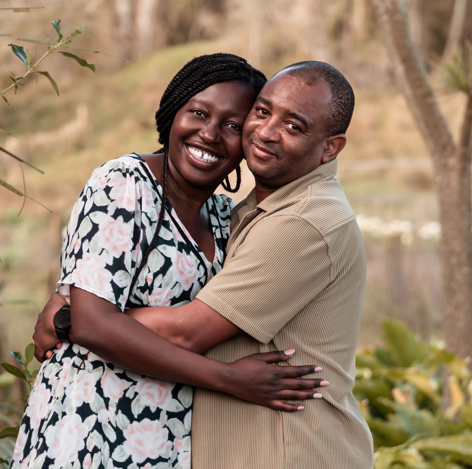 Happy couple embracing and smiling together in a lush outdoor garden setting.