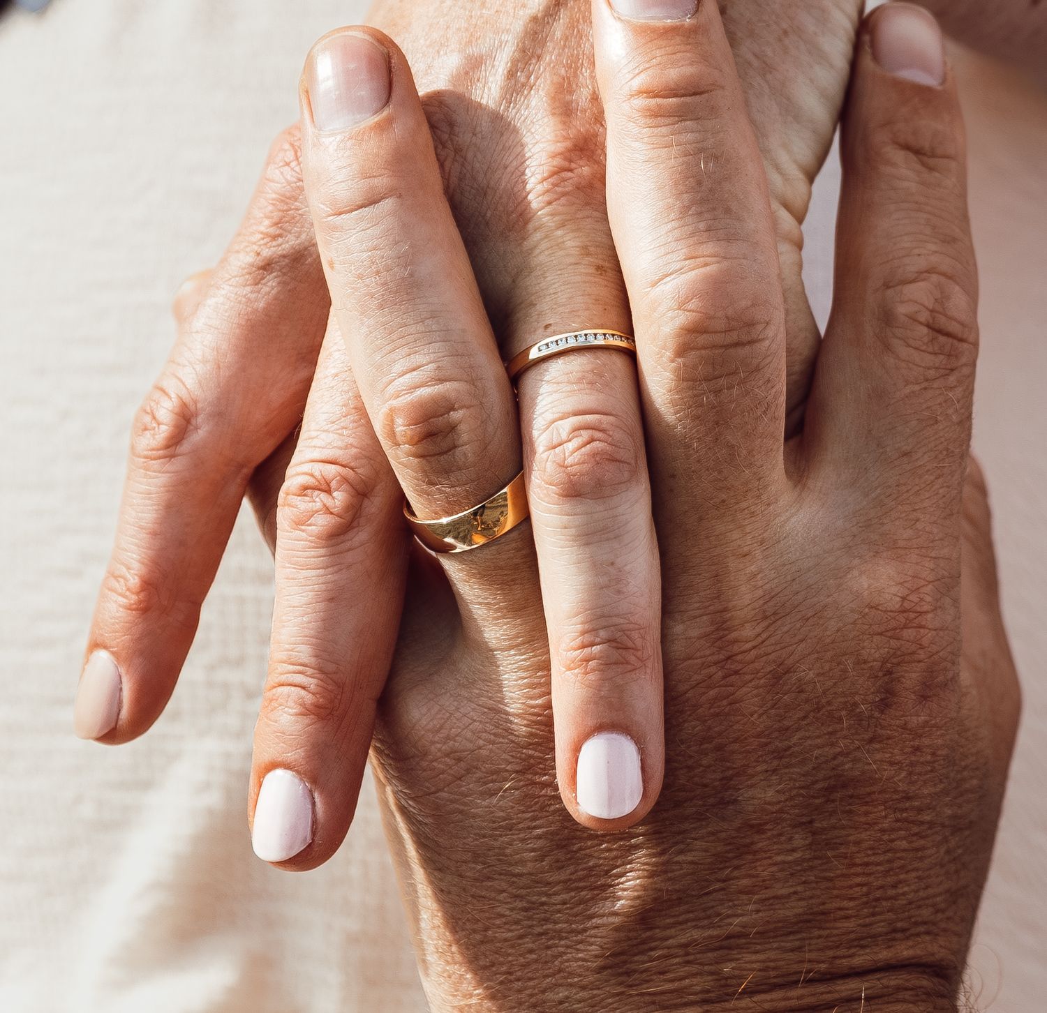 Close-up of newlyweds hands showing gold and diamond wedding rings after ceremony.