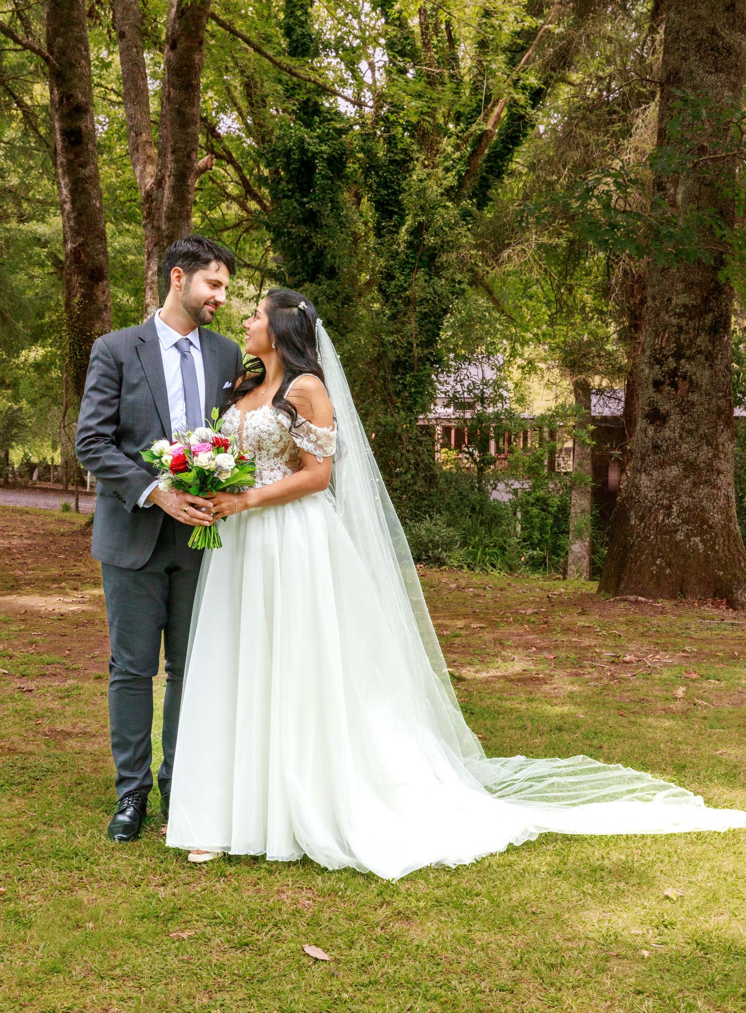 Bride and groom sharing romantic moment in lush green forest on wedding day.