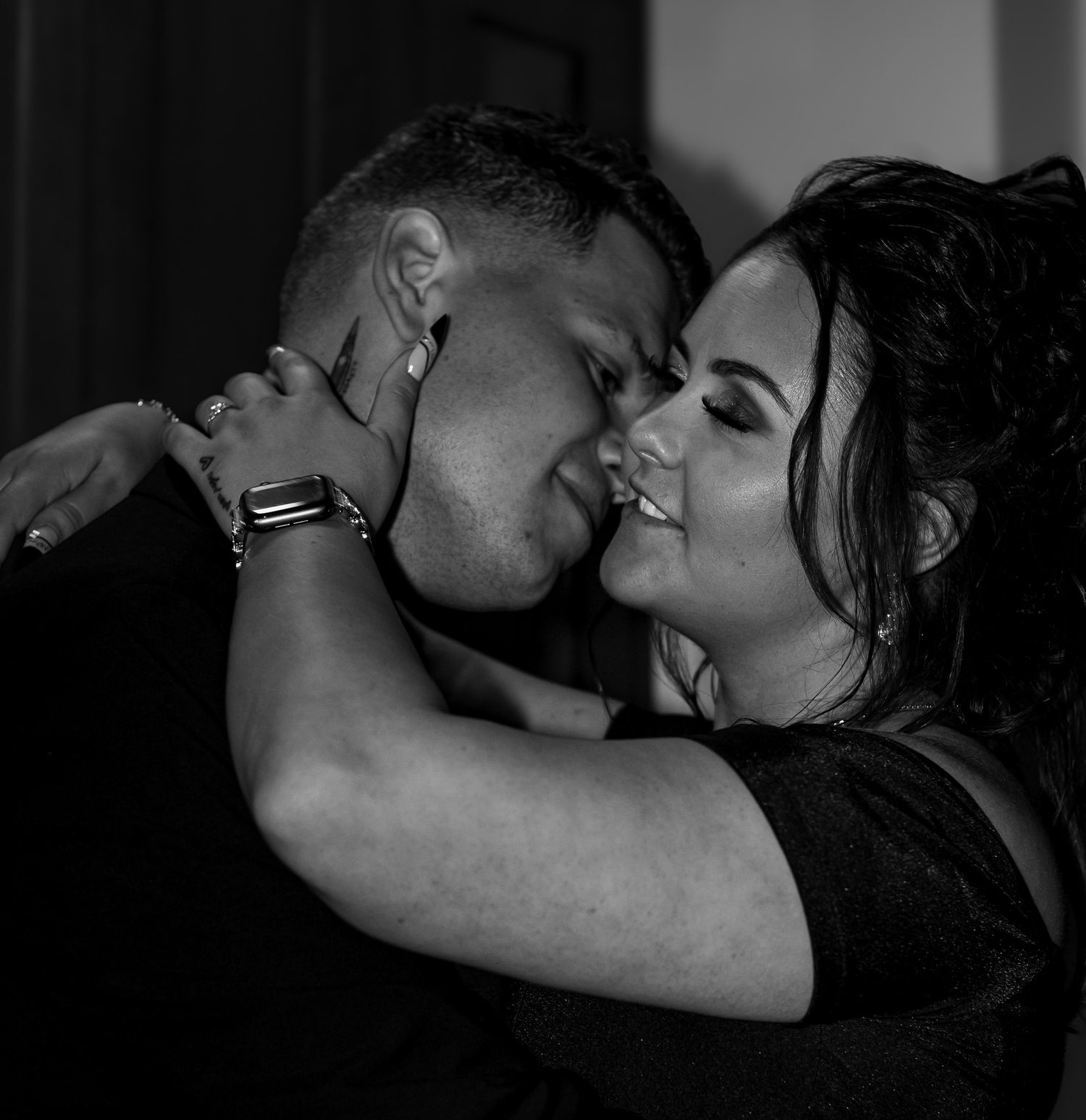 Black and white romantic couple embracing and smiling tenderly in an intimate moment.