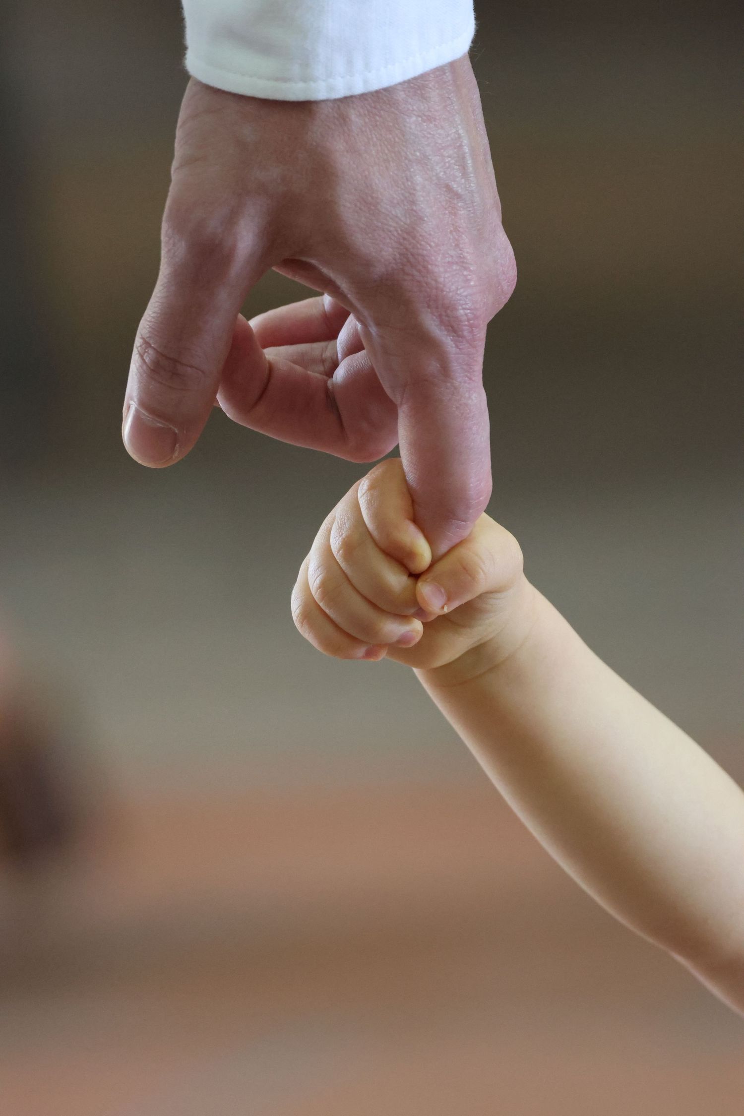 A small child's hand gripping an adult's finger, symbolizing trust, love, and the bond between parent and child.