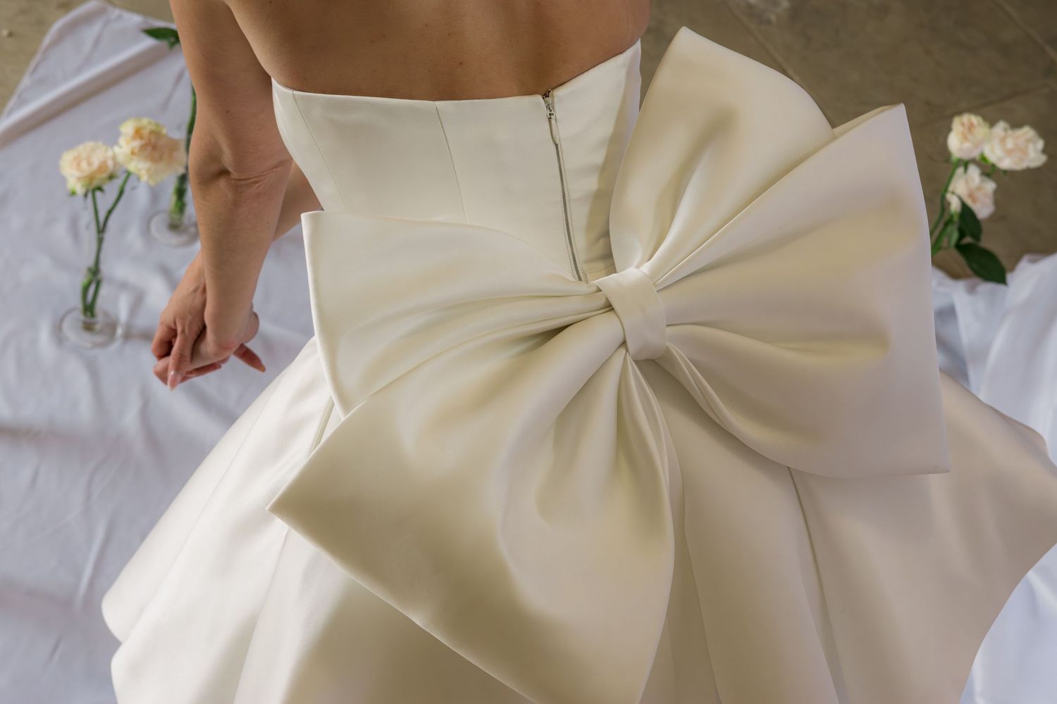 Close-up of an ivory wedding dress featuring an elegant large satin bow detail at the back waist.