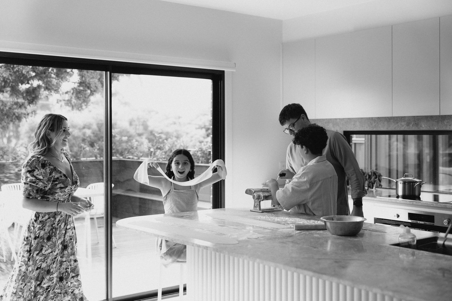 Black and white photo of a family cooking together in a modern kitchen Airport West Melbourne.