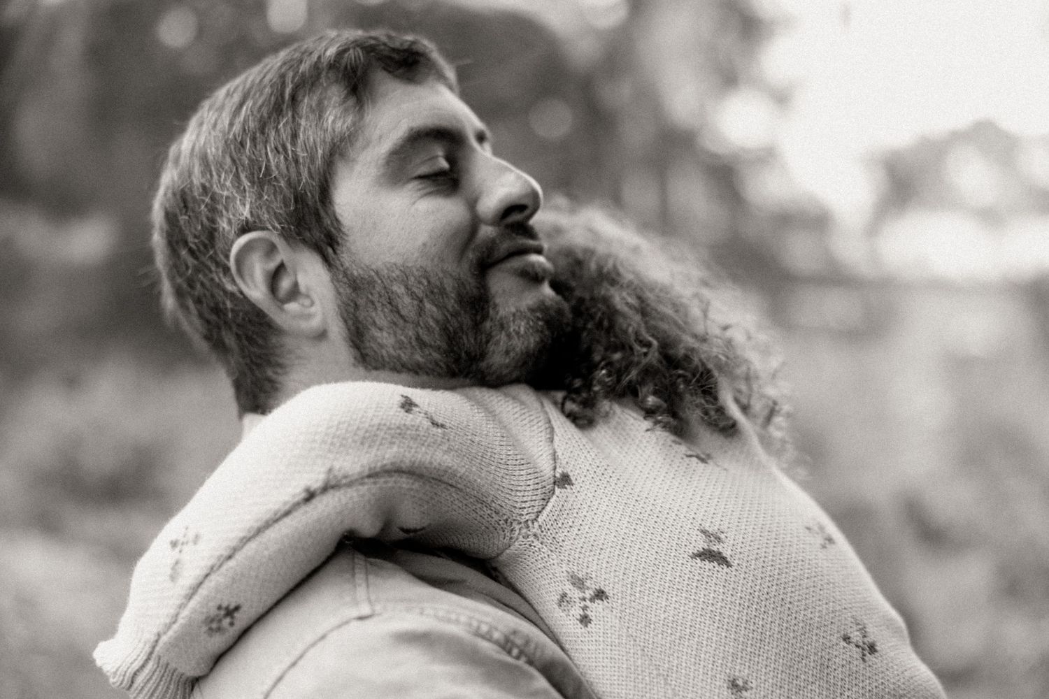 Black and white portrait of a father holding daughter with curly hair in Newport Lake Reserve.