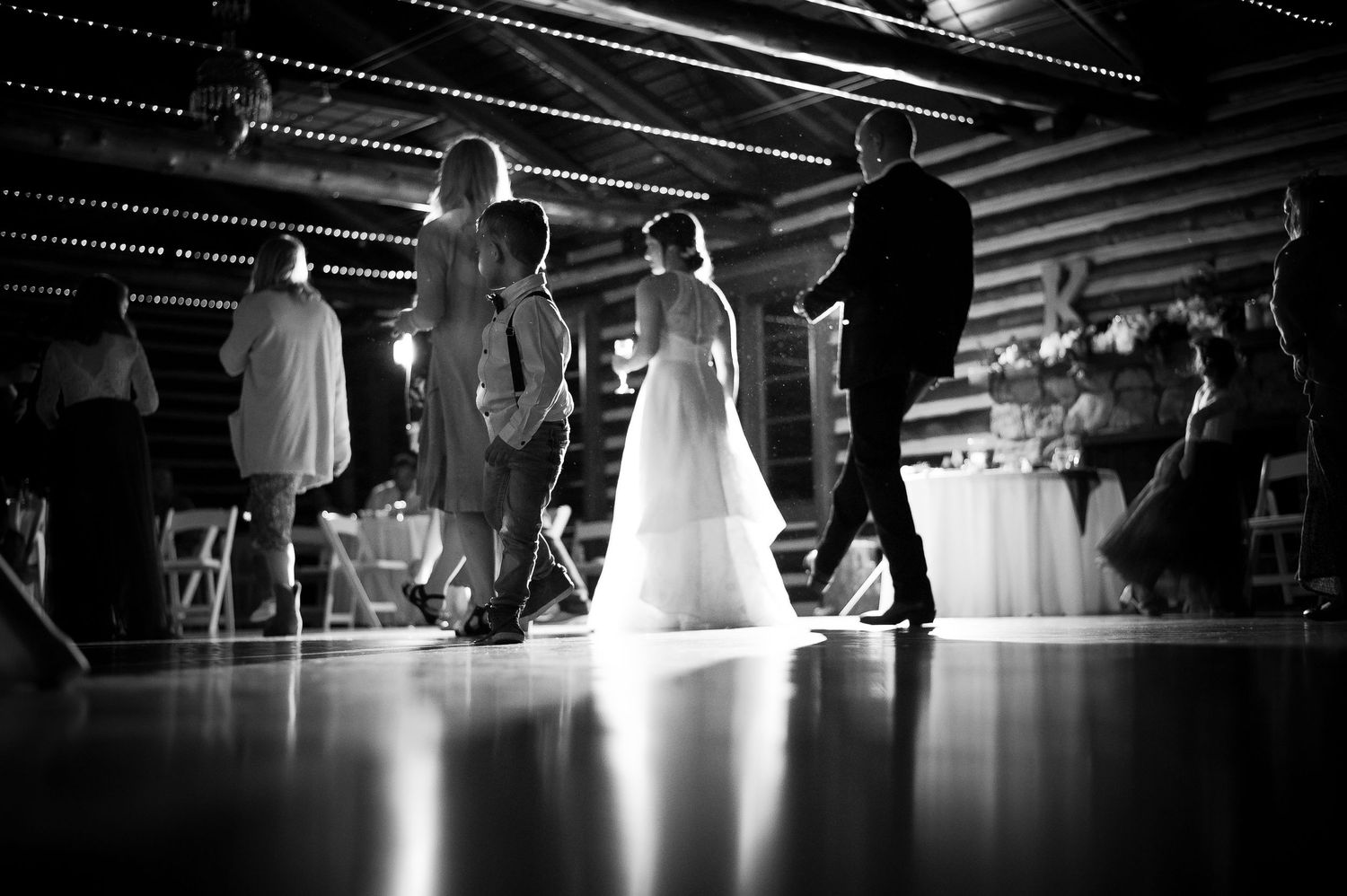 Black and white photo of bride and groom sharing first dance at rustic wedding reception.