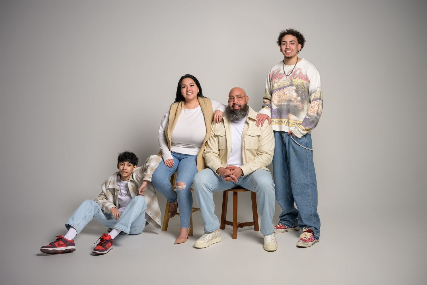 Family of four in casual denim outfits posing for relaxed modern studio portrait photography.