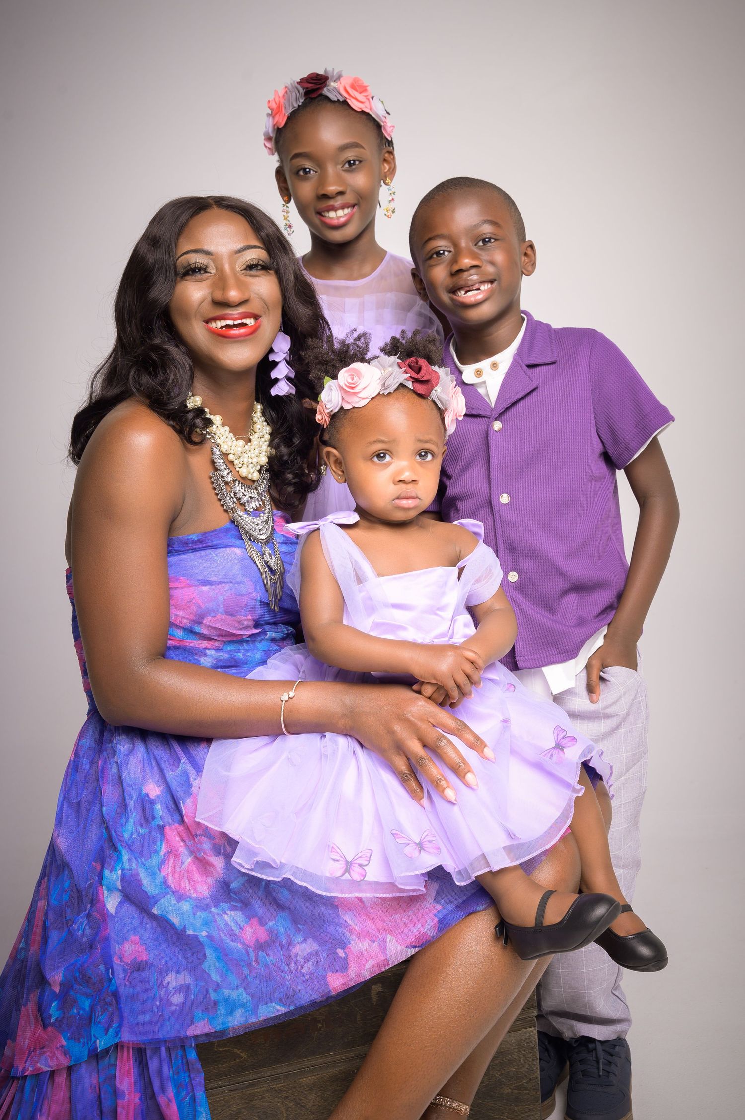 A joyful mother poses with her three children in purple outfits for a family portrait.