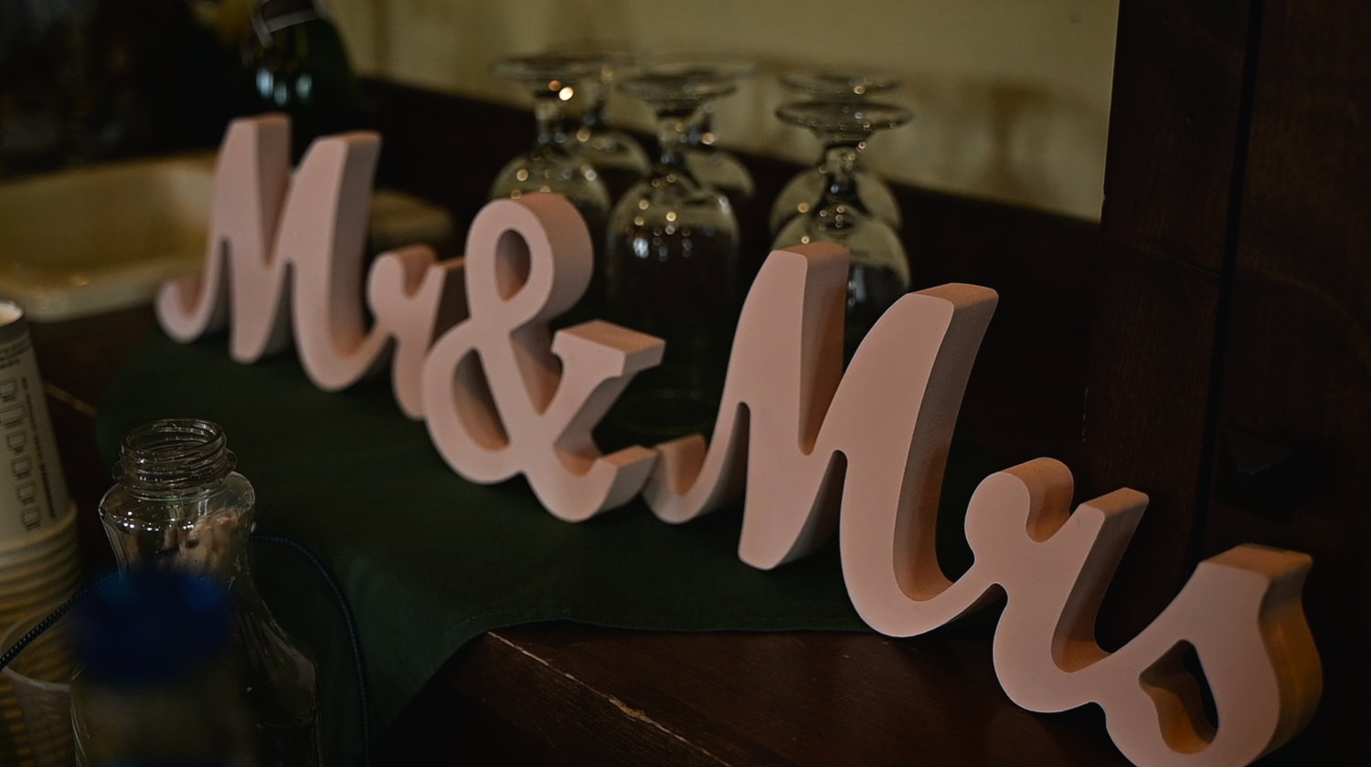 Decorative pink Mr & Mrs wooden letters displayed on a table at a wedding reception venue.
