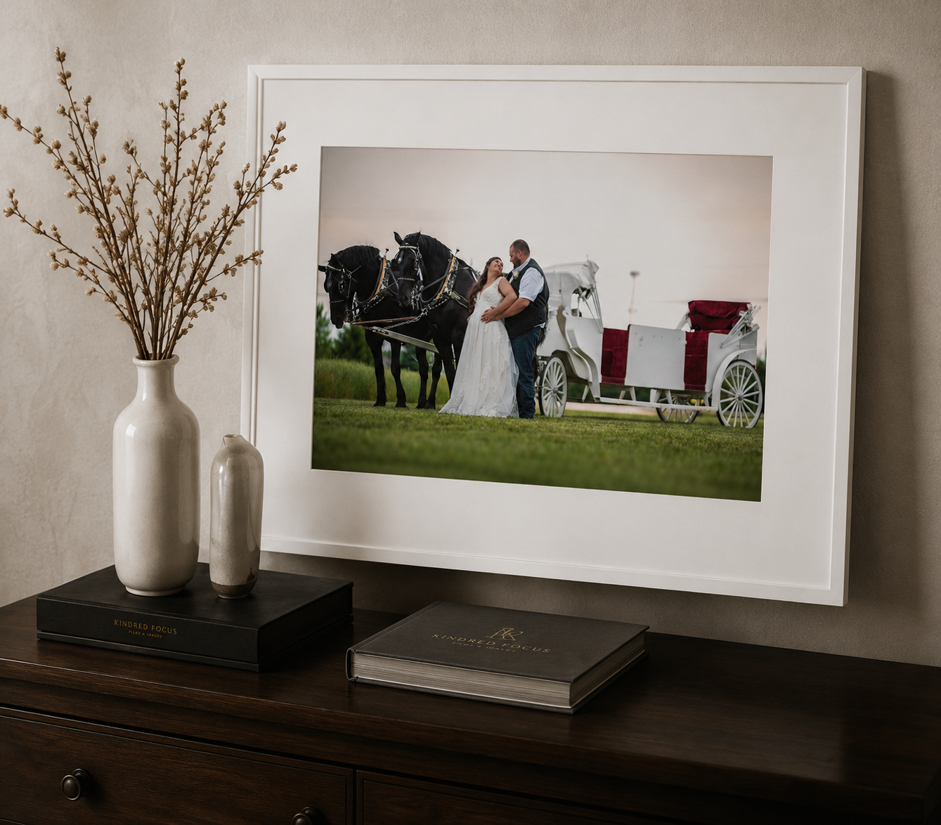 Framed wedding portrait of couple with horse-drawn carriage displayed on dark wood dresser.