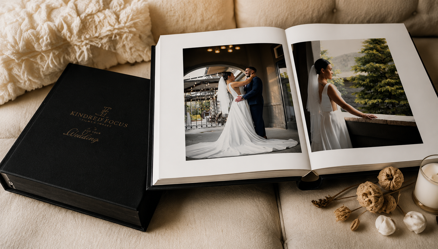 Luxury black leather wedding photo album open displaying professional wedding portraits on sofa.
