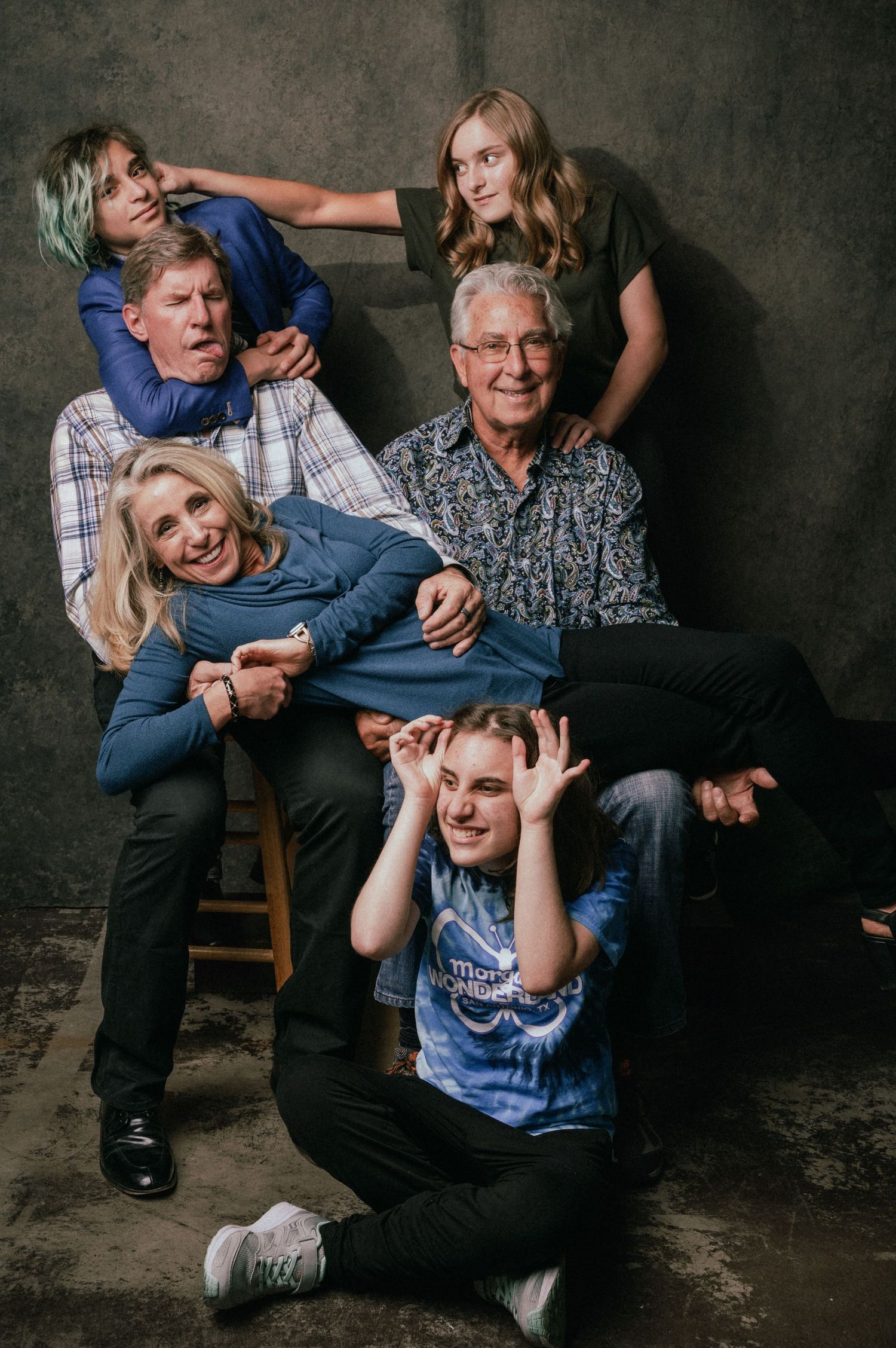 A multigenerational family of six making fun silly faces together in a studio portrait.