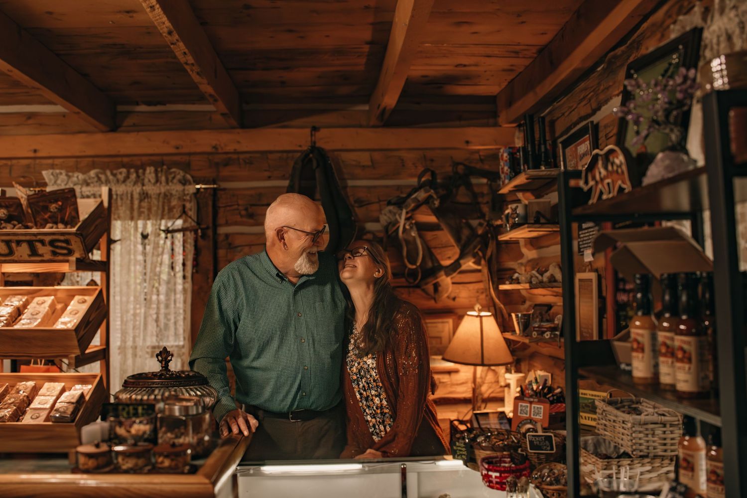 Elderly couple sharing a tender moment in a rustic wooden cabin shop filled with country goods.