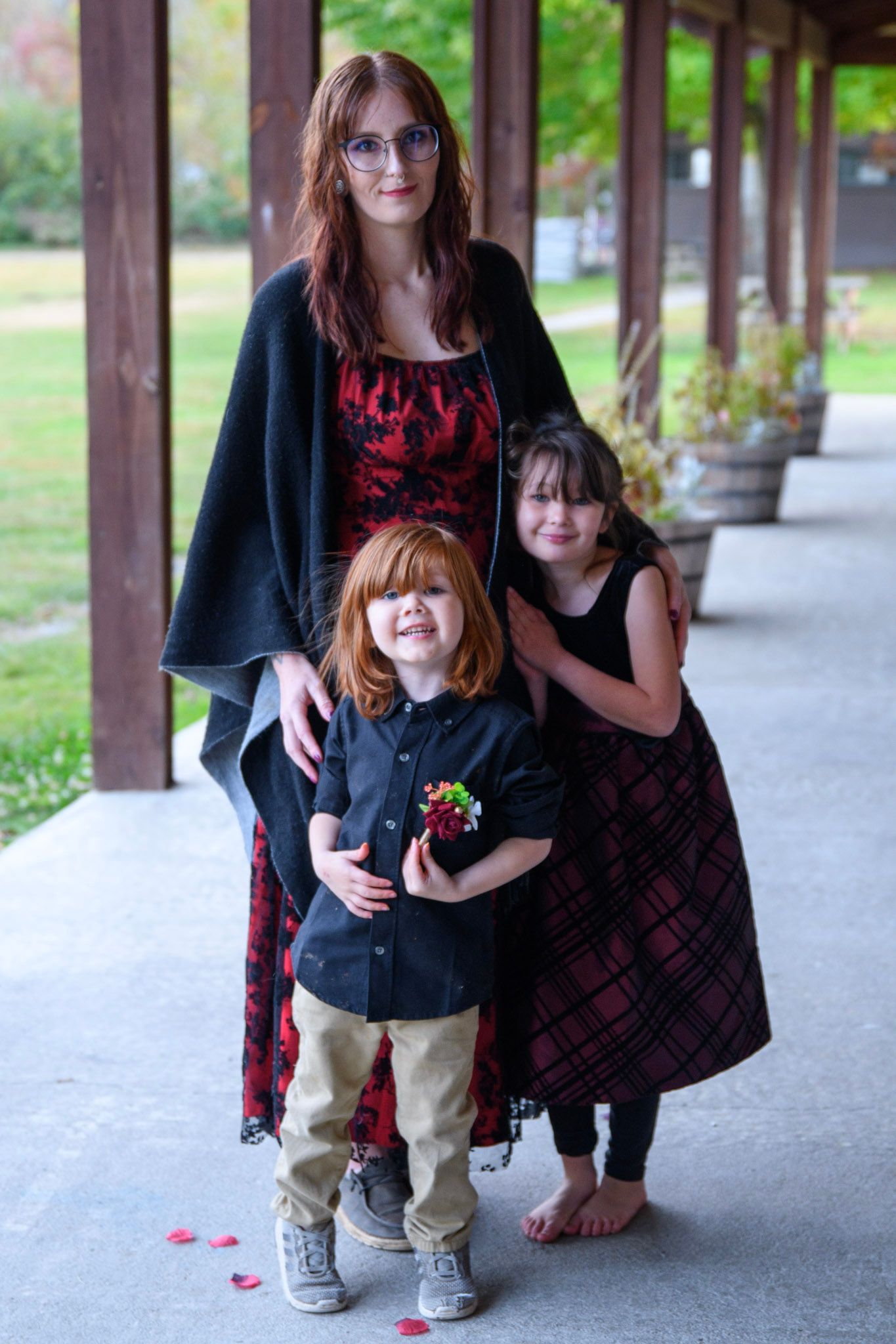 Mother with two children posing under a covered walkway in autumn park.