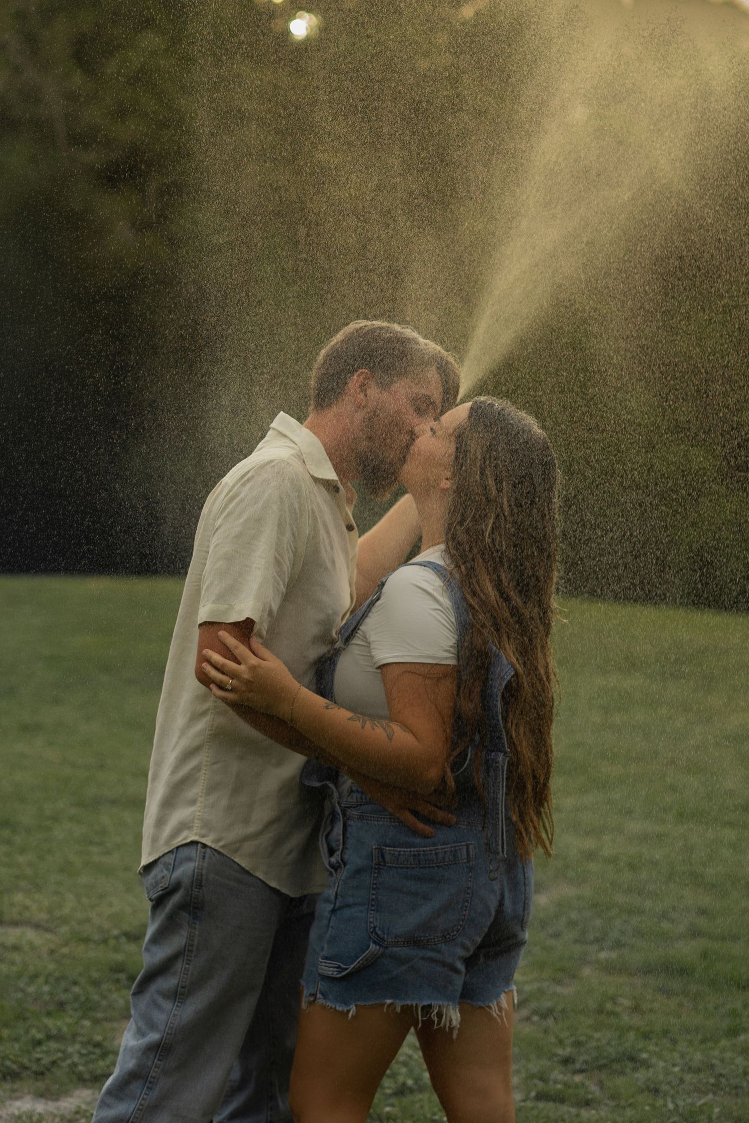 A man and woman kissing under water being sprayed from a hose