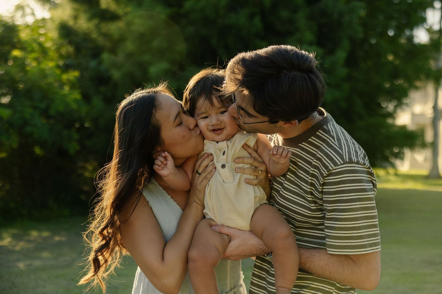 Man and woman kissing a baby on each cheek