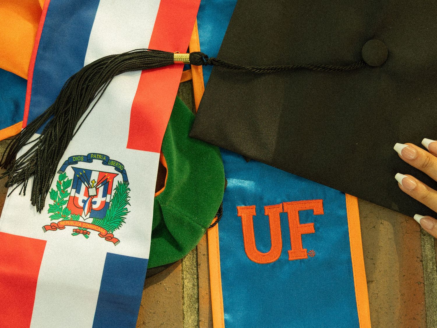 A flat lay of objects including an orange and blue UF stole, a flag stole, and a black graduation cap.