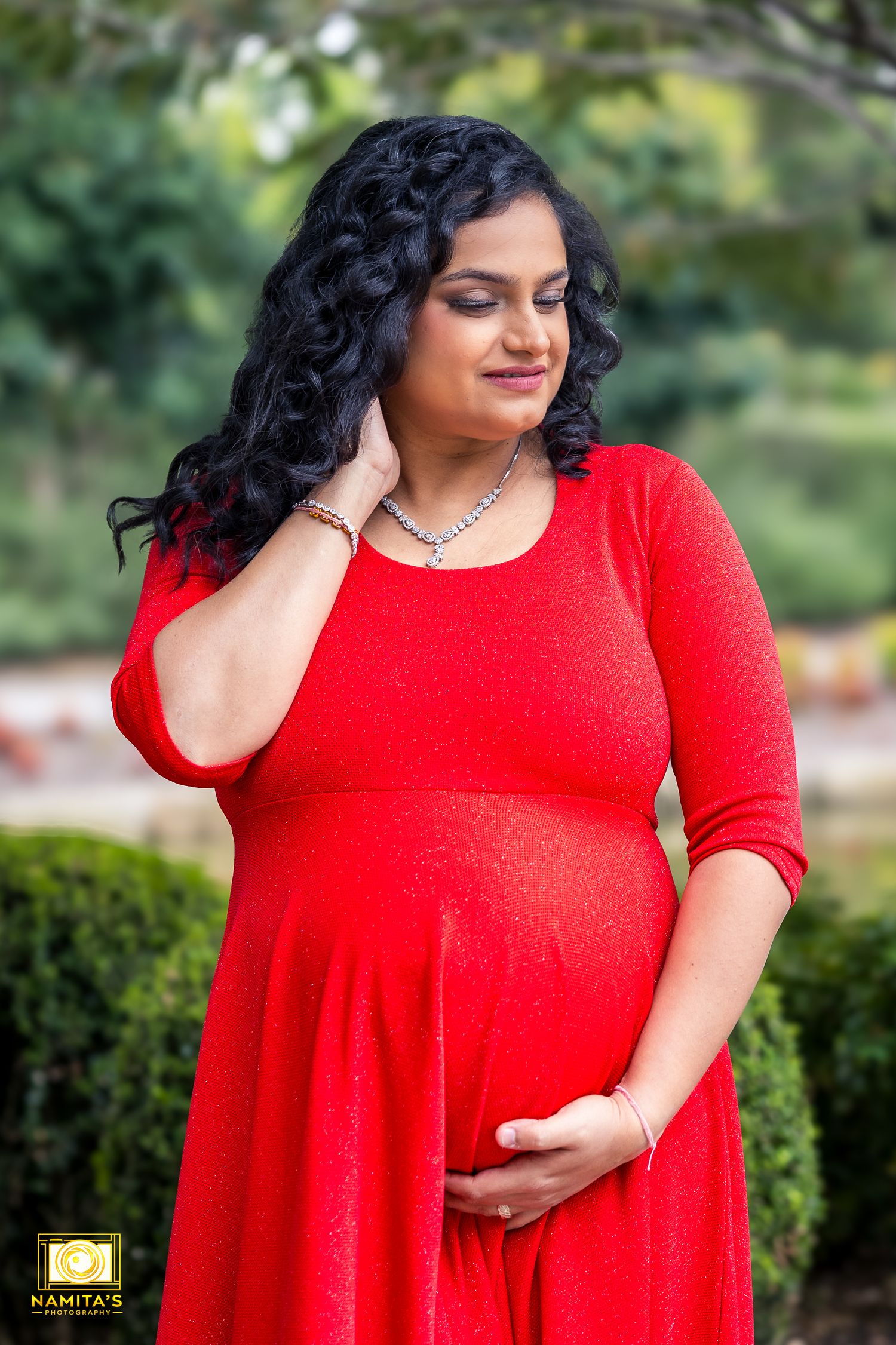 Maternity photography client holding baby bump in natural outdoor setting