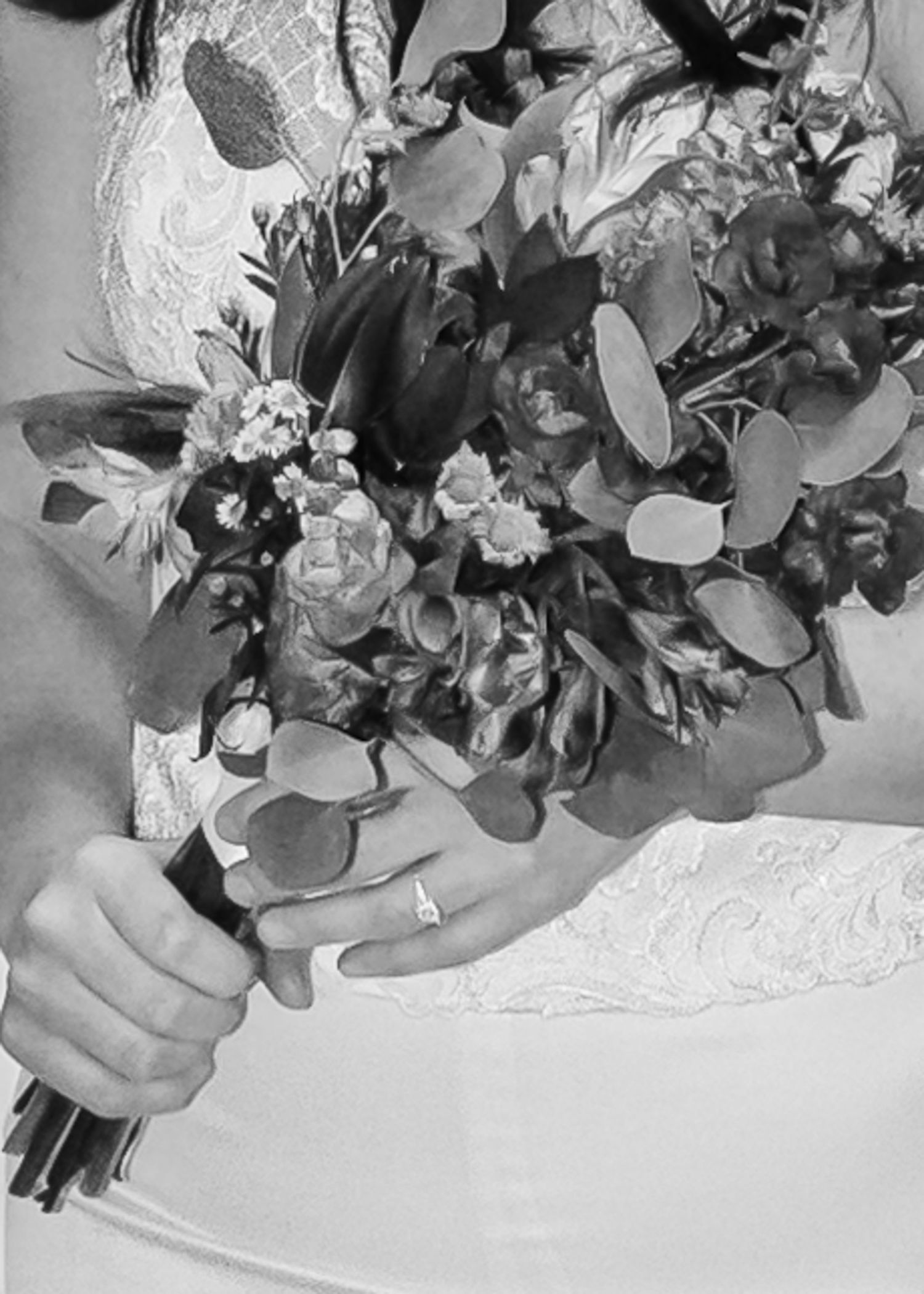 Black and white close-up of bride holding lush wedding bouquet with ring visible on her finger.