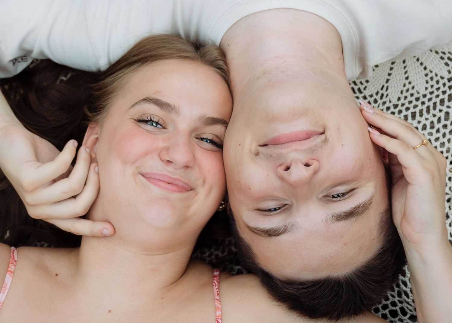 Smiling couple lying down facing each other in a playful and affectionate overhead portrait shot.