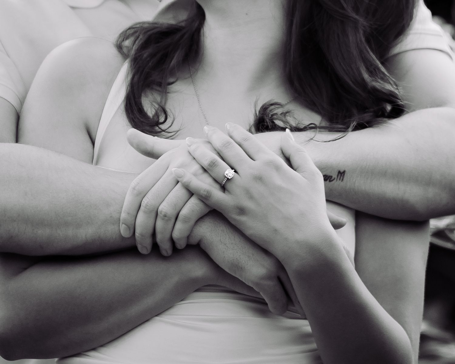 Black and white photo of a couple holding hands, woman wearing an engagement ring, romantic close-up shot.