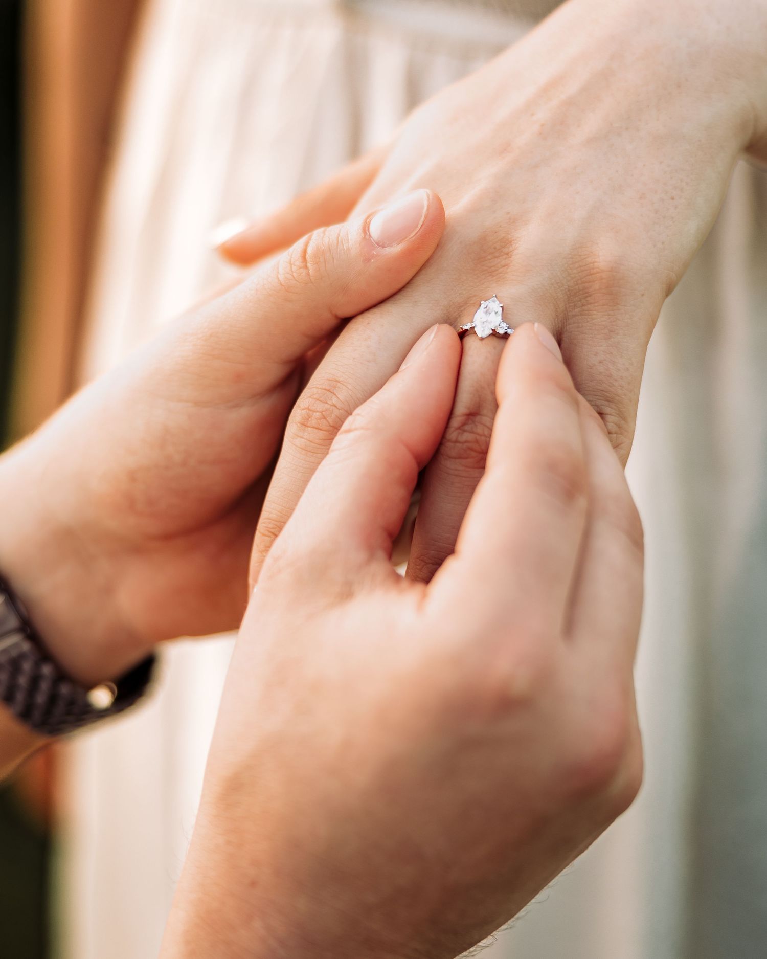 Close-up of a diamond engagement ring being placed on a woman's finger during a romantic proposal.