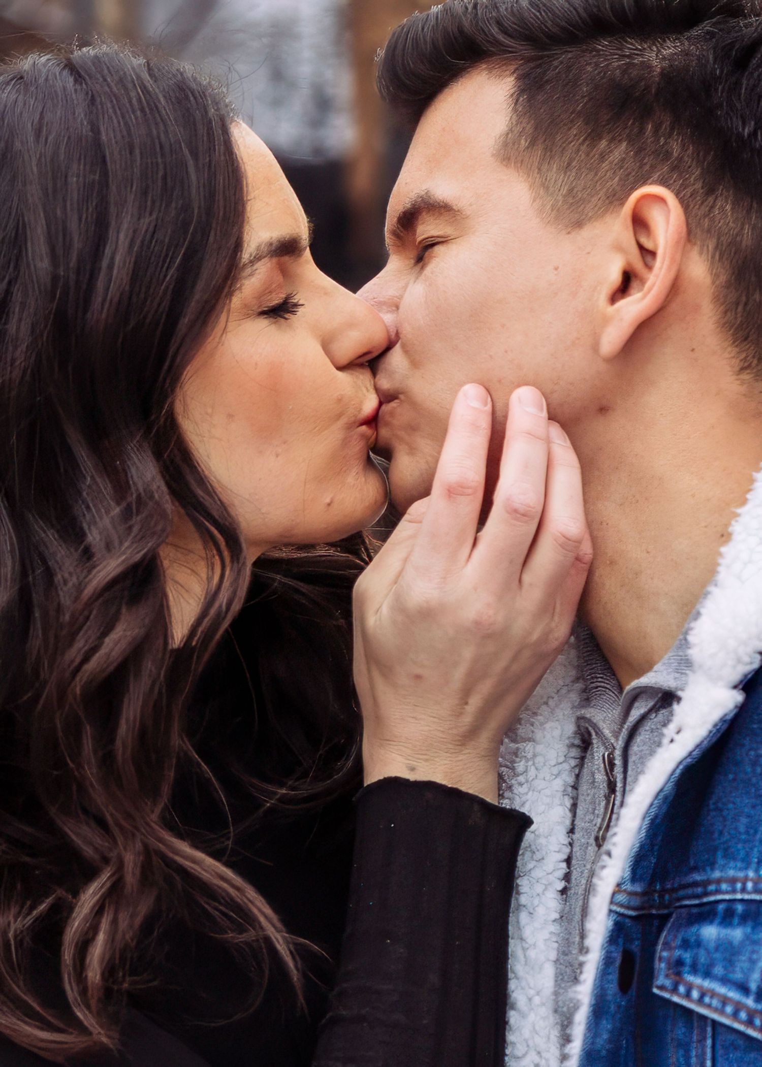 Close-up of a couple sharing a tender kiss with the woman gently holding his face.