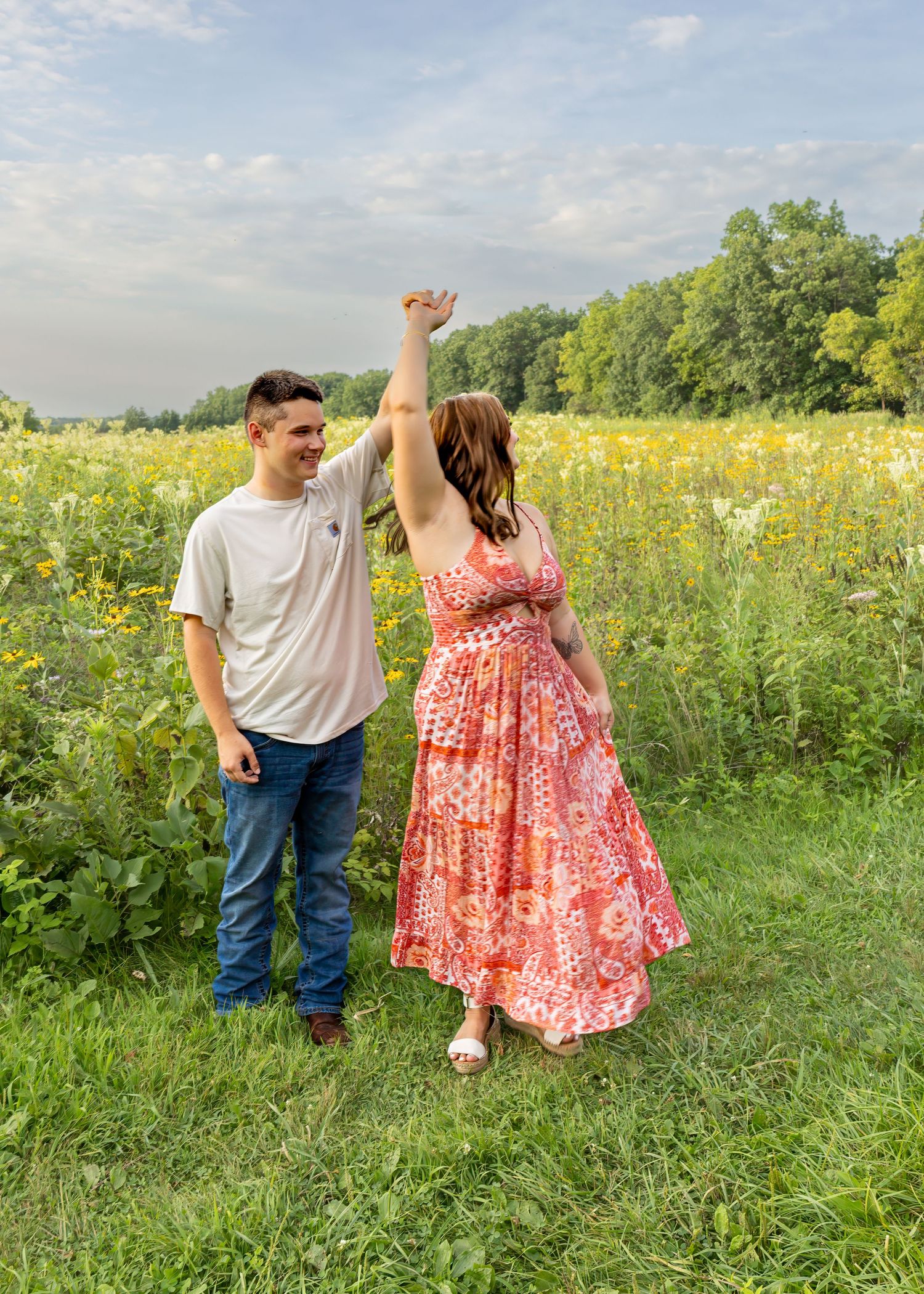 Couple dancing in a vibrant wildflower meadow, woman in floral dress twirling joyfully.