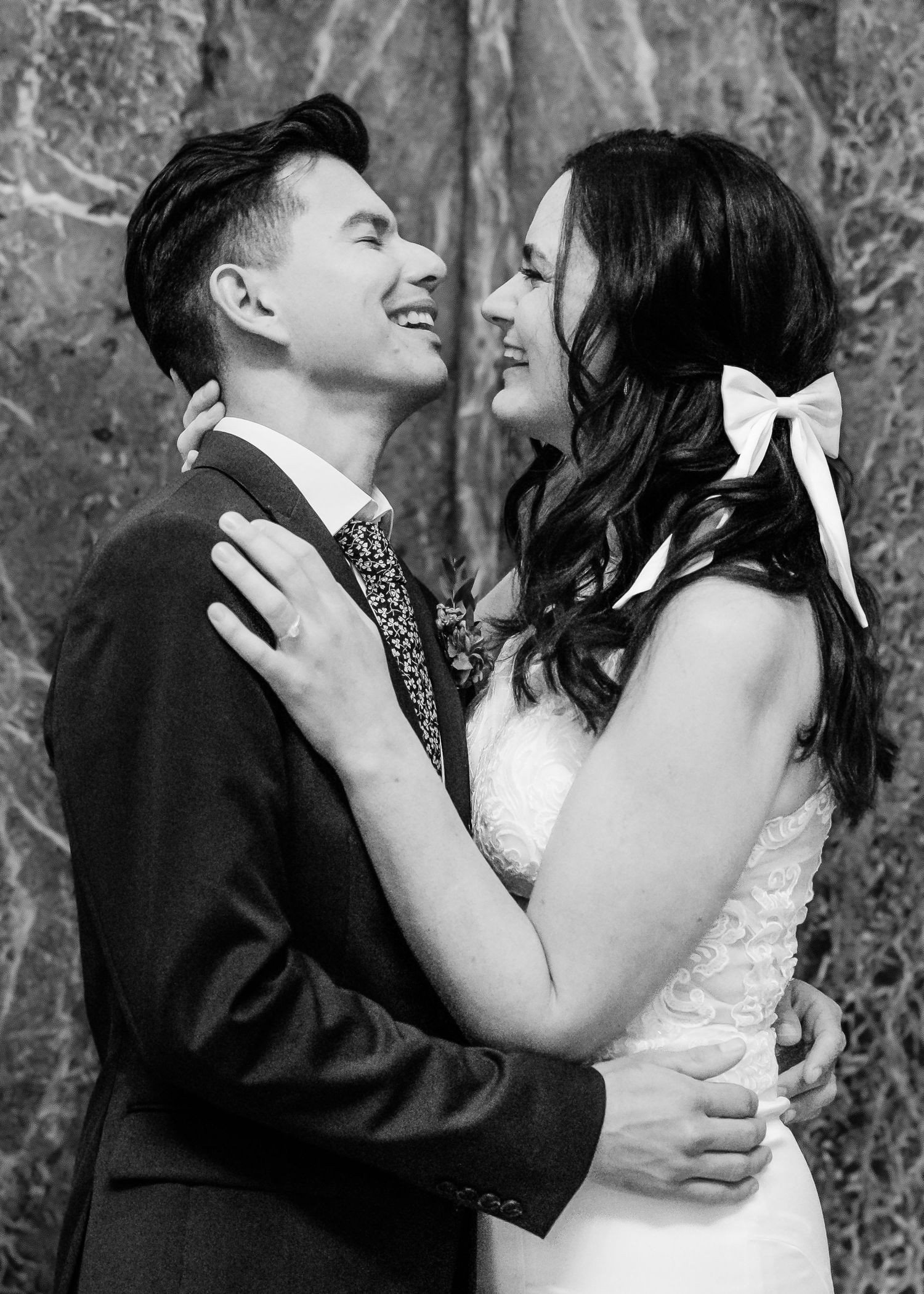 Black and white portrait of smiling newlyweds embracing tenderly after wedding ceremony.