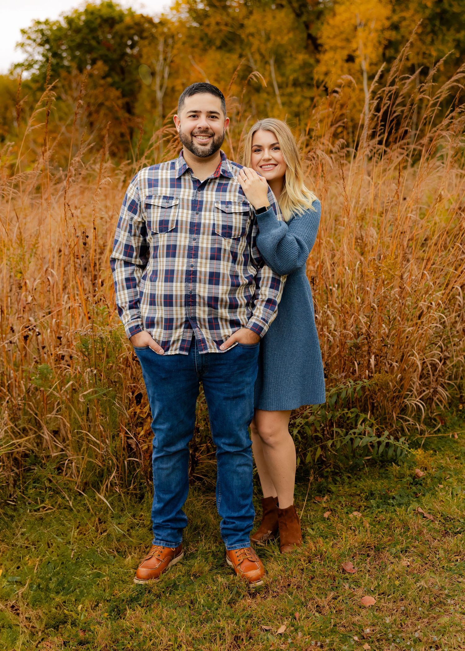 Smiling couple poses together in autumn field with golden tall grass background.