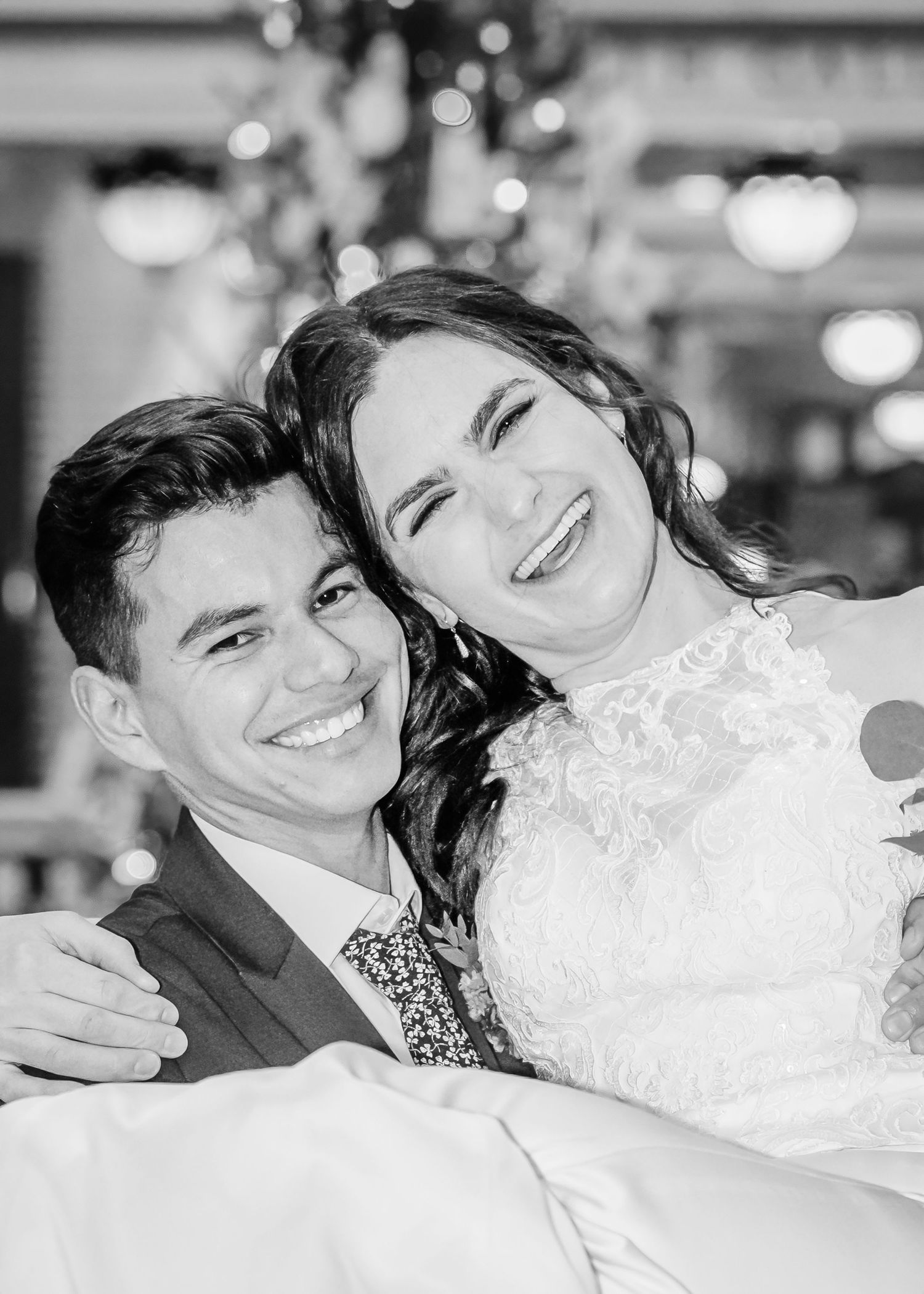Happy bride and groom share a joyful close-up black and white wedding portrait.