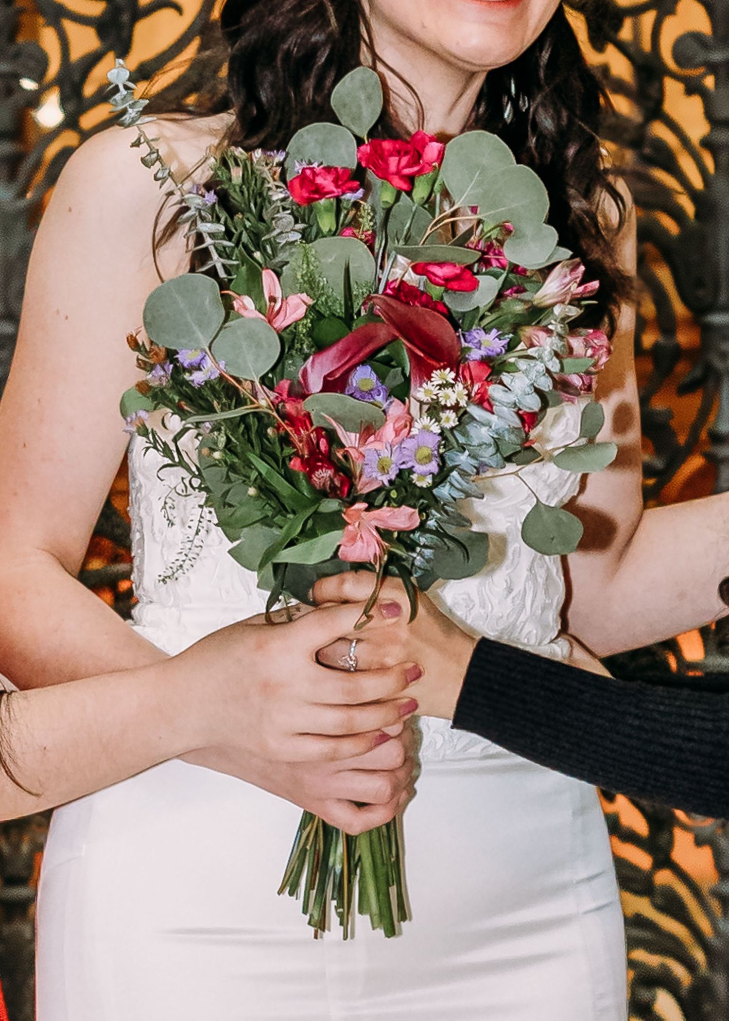 Bride holding colorful wedding bouquet with pink roses, eucalyptus, and mixed wildflowers.