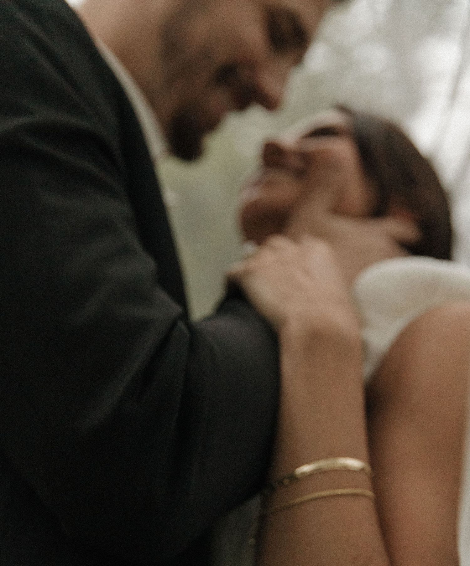 Close-up shot of a tender wedding moment with an intimate embrace and delicate jewelry details.