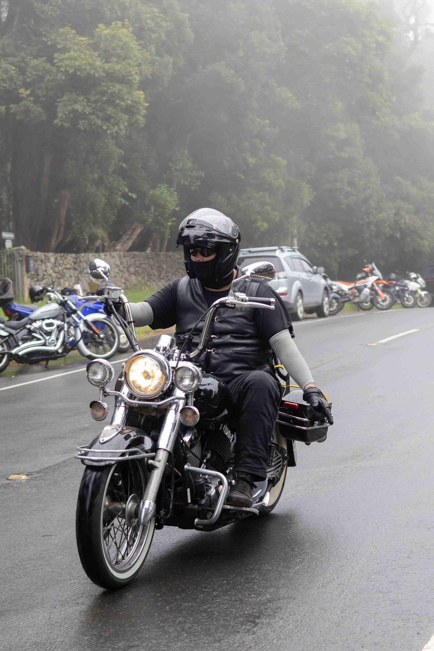 Cruiser motorcycles riding through misty conditions on a mountain road.