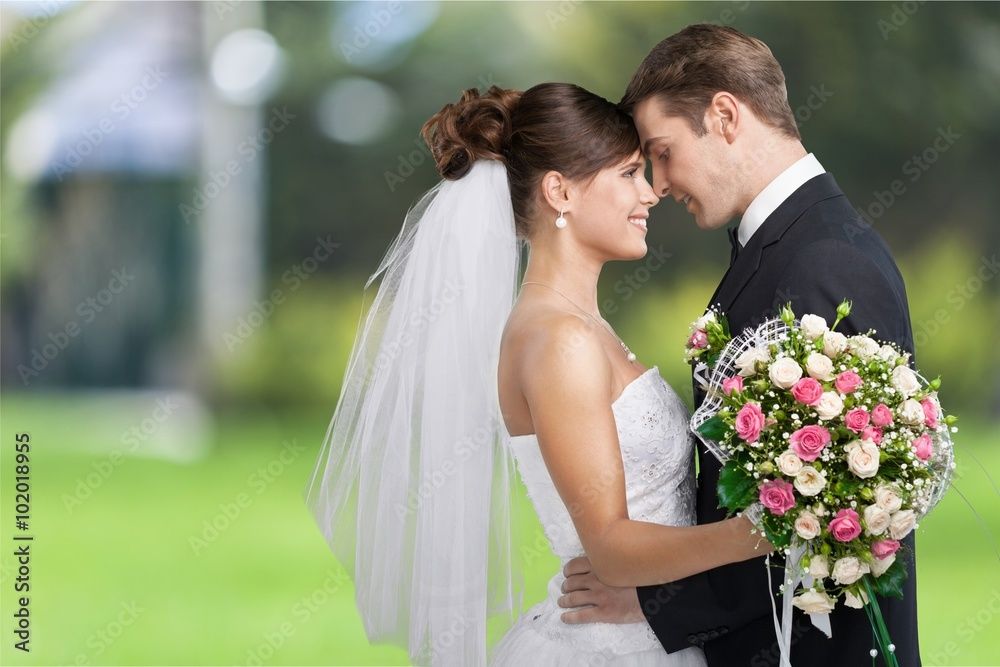 Romantic outdoor wedding portrait with bride holding pink and white floral bouquet.