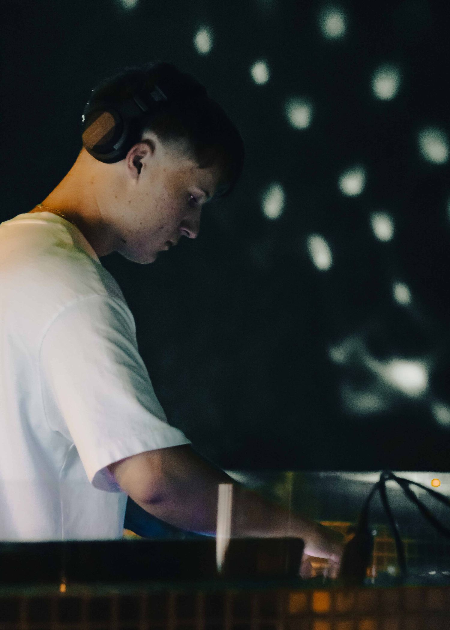 DJ performing at a nightclub under spotlights and disco ball reflections.