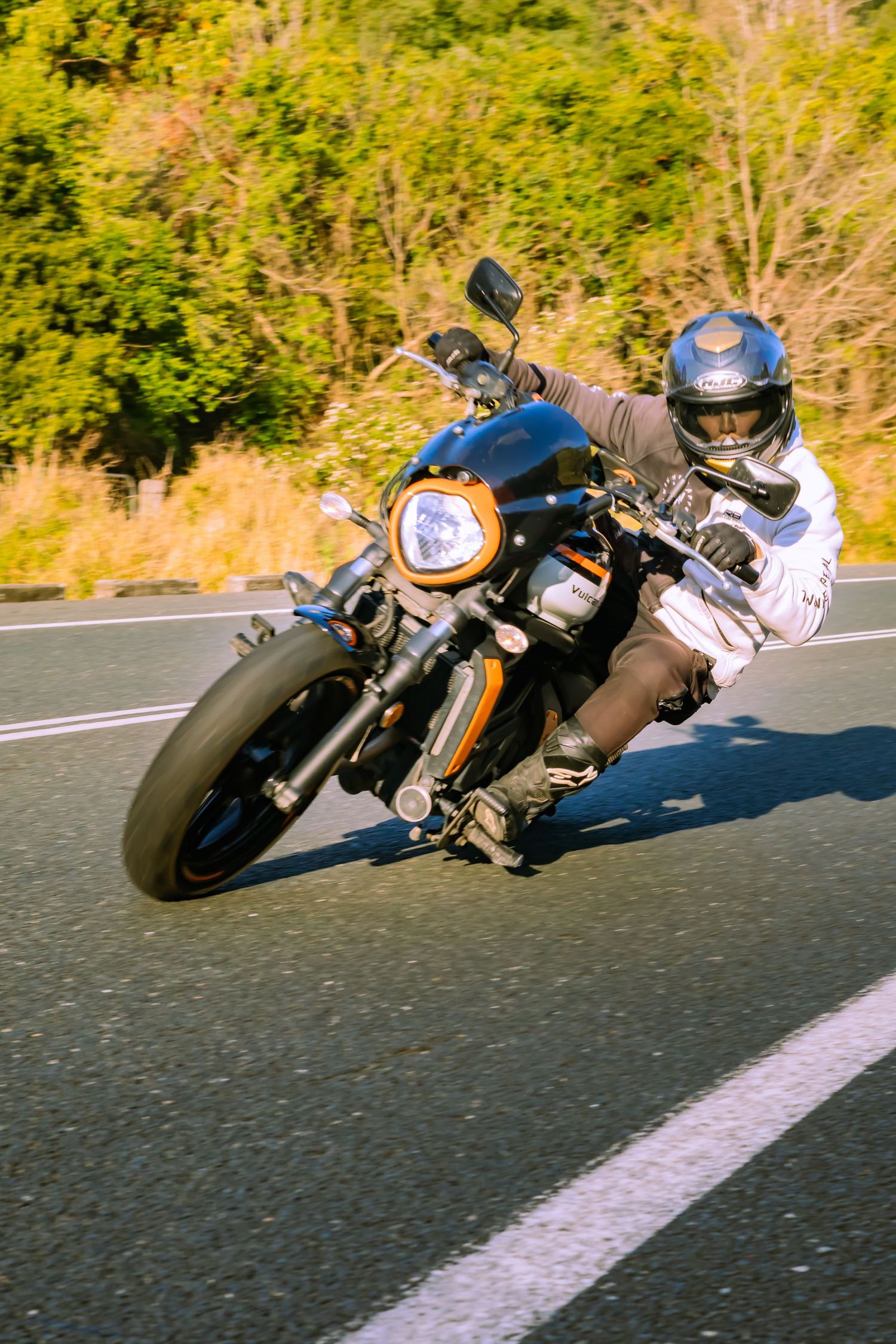 Multiple motorcycles leaning into a curve on sunny mountain road.