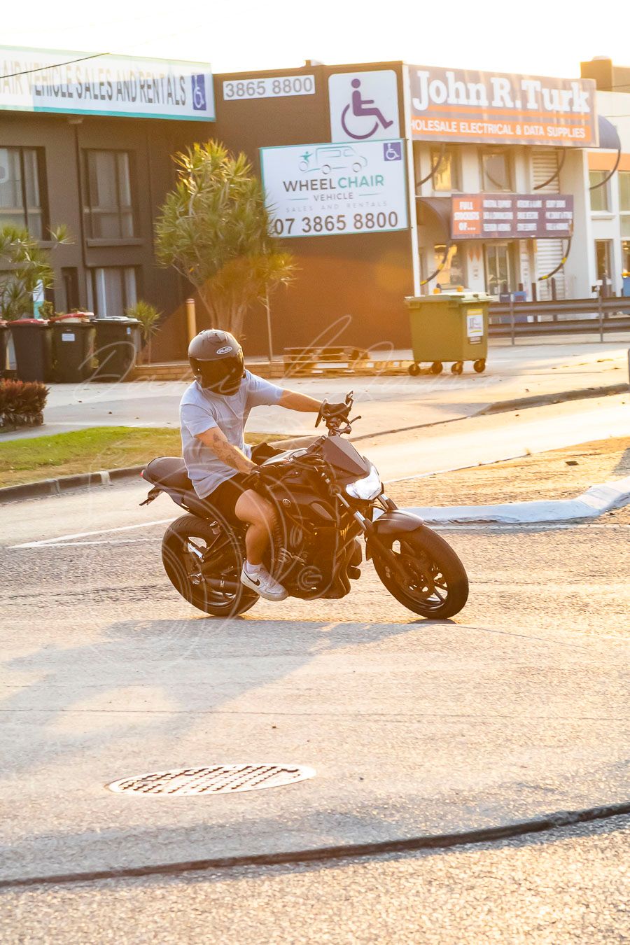Custom motorcycle parked outside commercial buildings in warm sunset lighting.