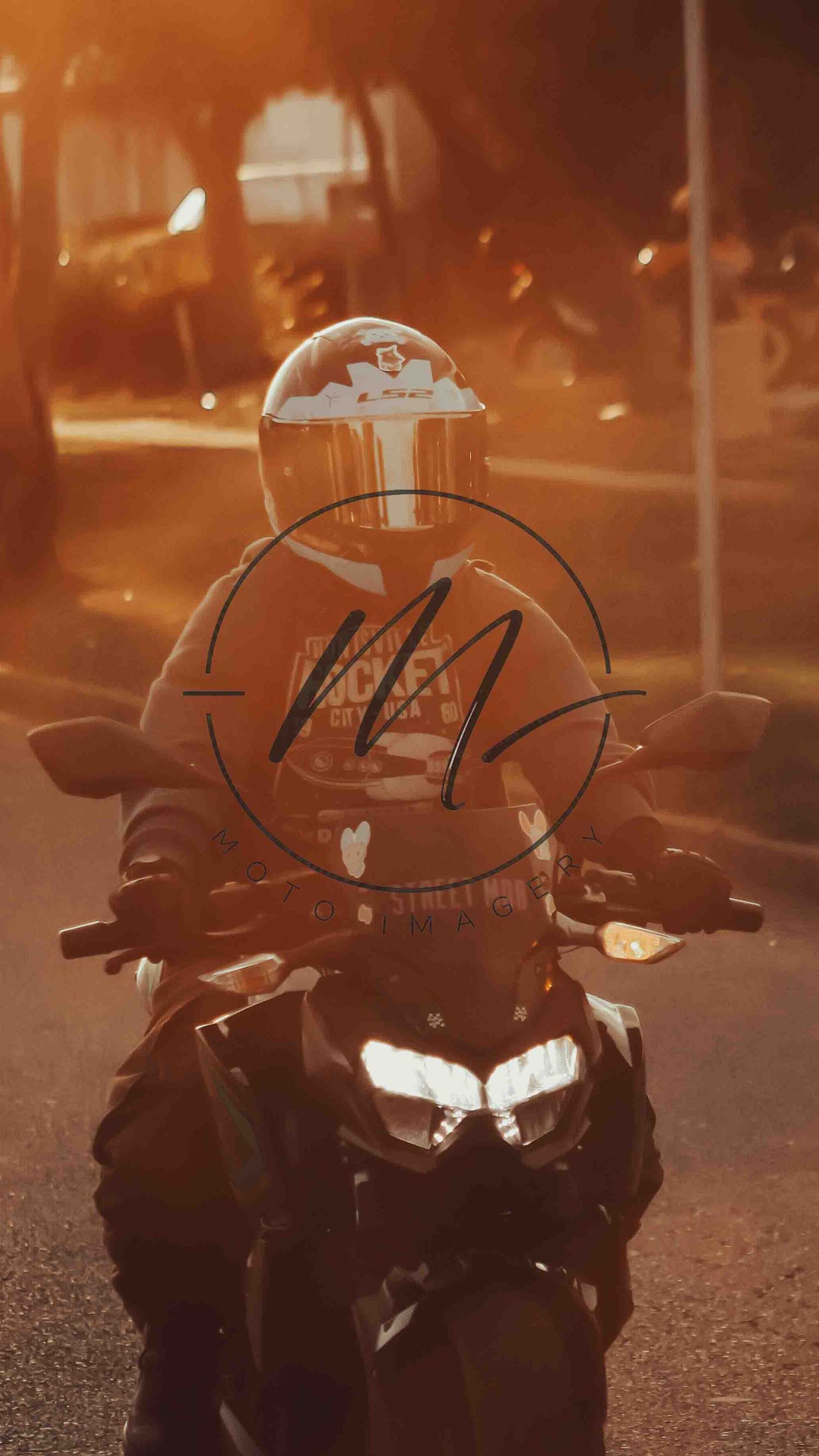 Motorcyclist in full helmet riding a sport bike on a road at golden hour with warm sunlight glowing in background.