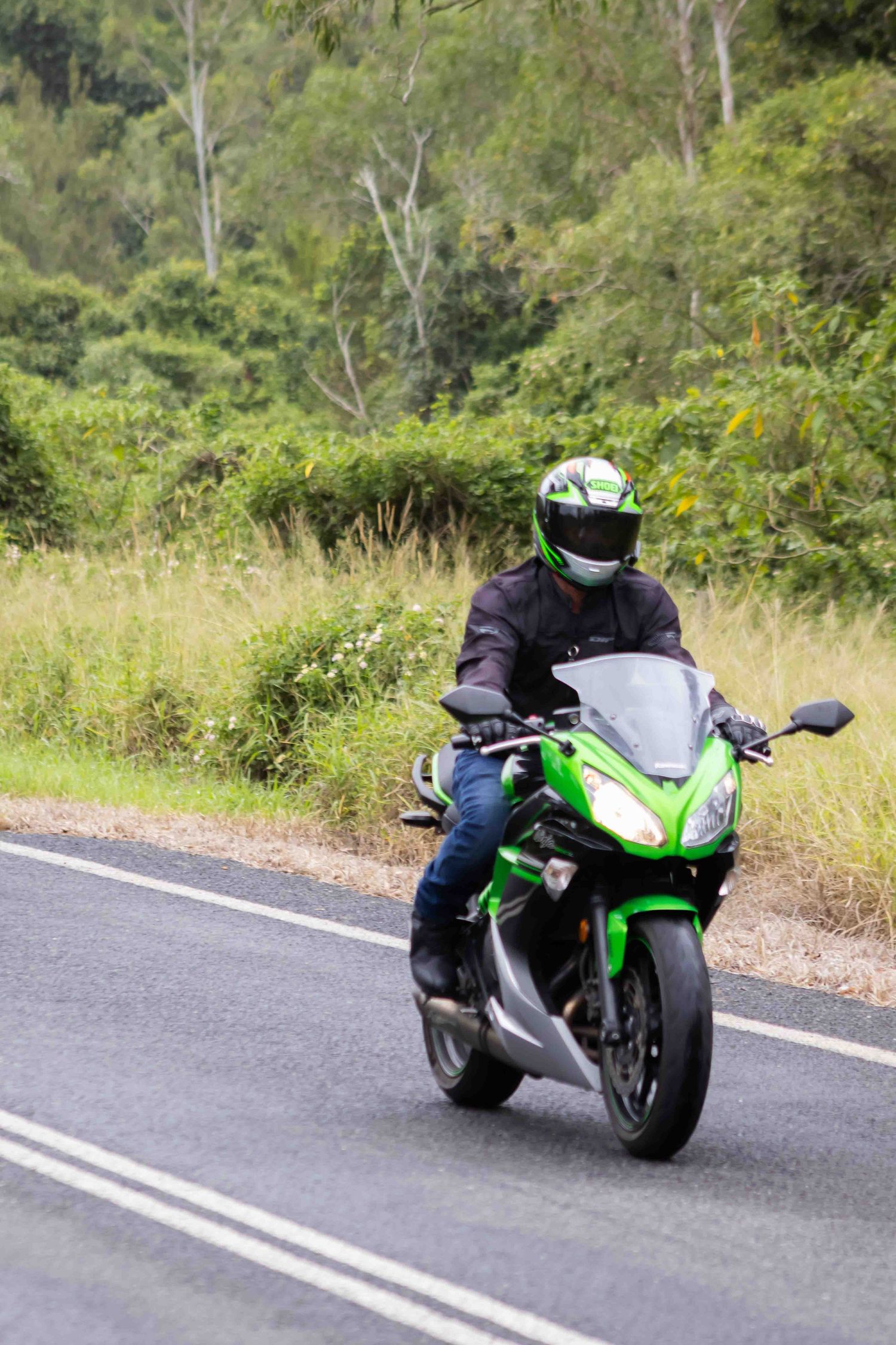 Green sport bike rider taking a curve on a mountain road.