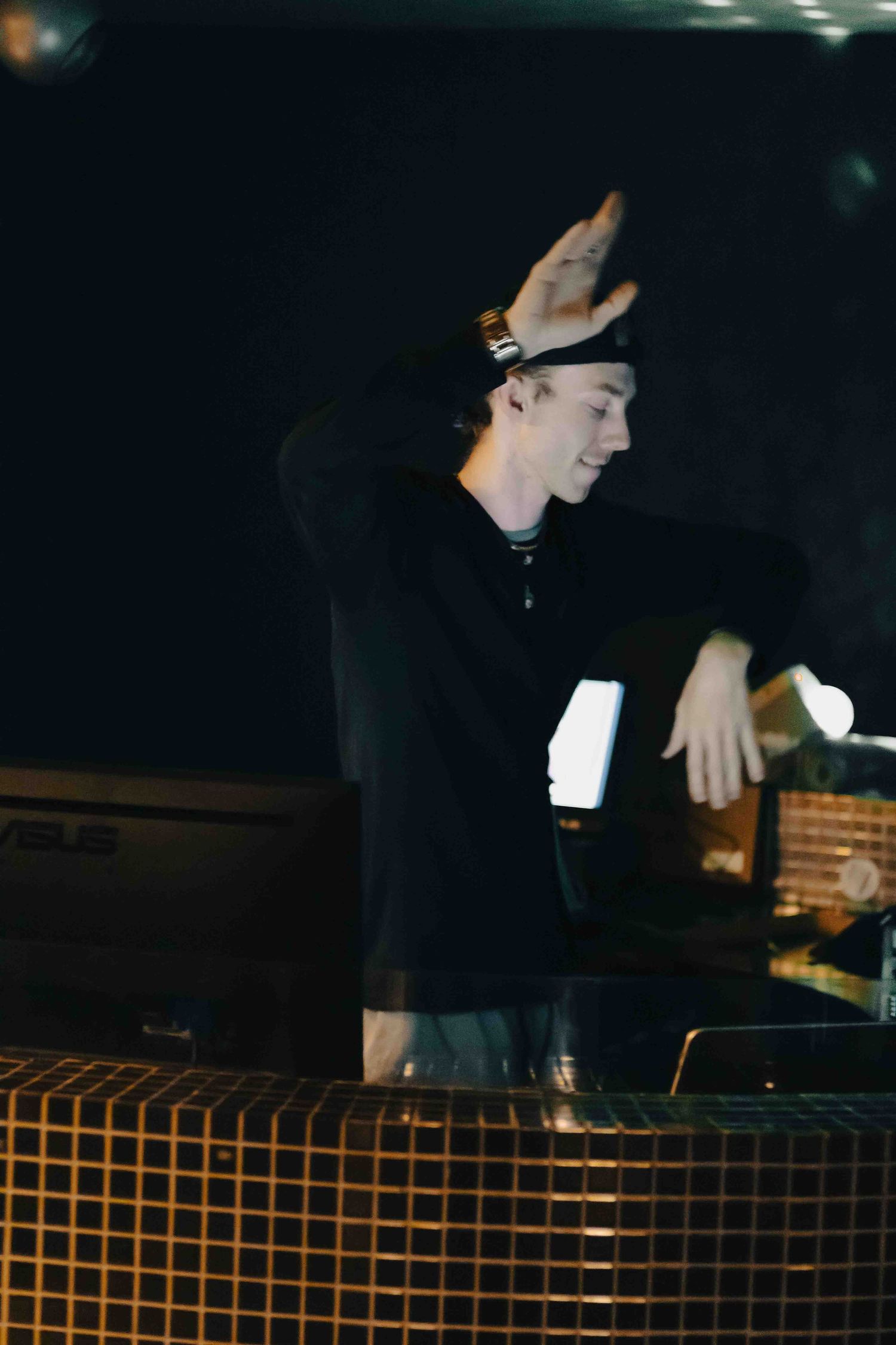 DJ working the controls at a nightclub under moody lighting.