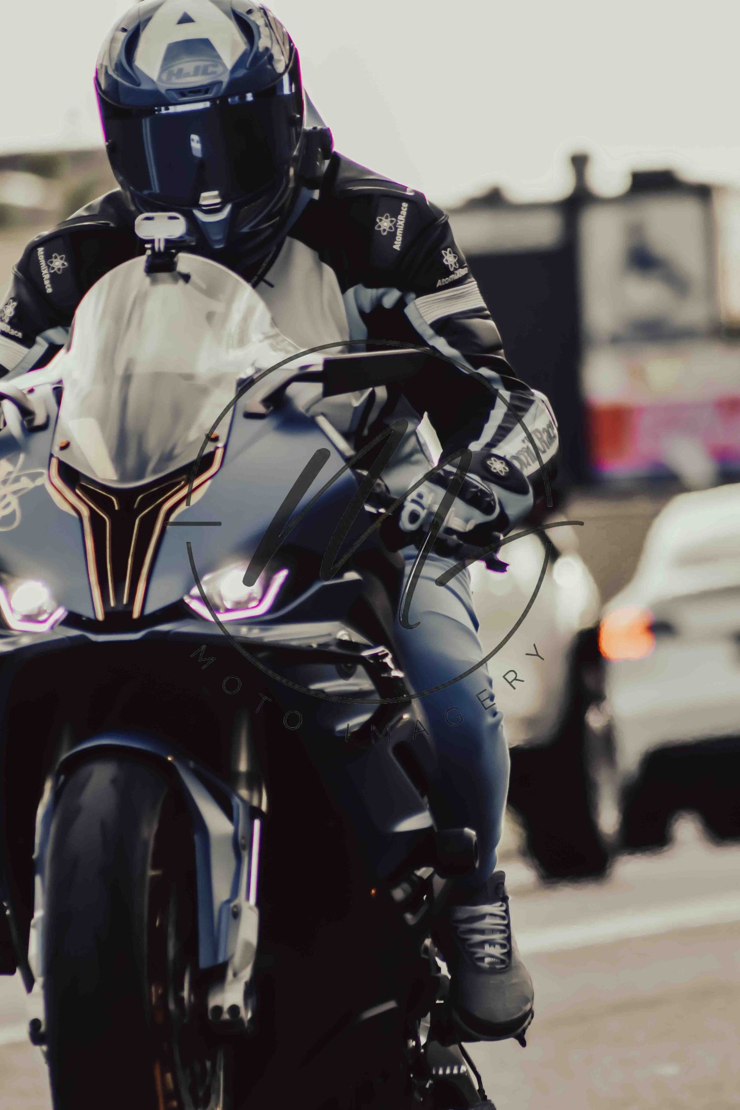 A motorcyclist in full black leather gear and helmet rides a sport bike with purple LED lights in traffic.