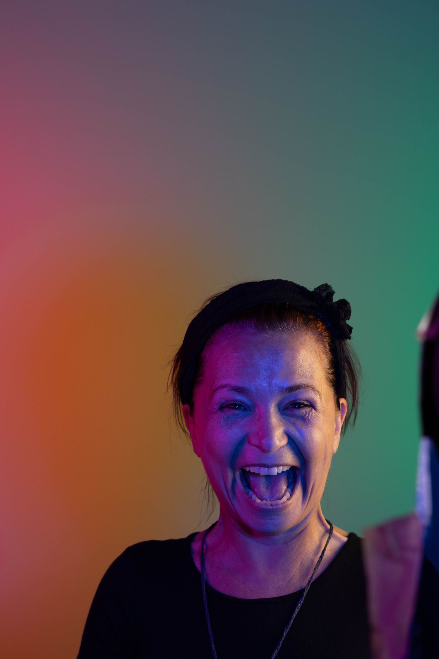 A colorful portrait lit with vibrant pink and teal lighting against a dark background.