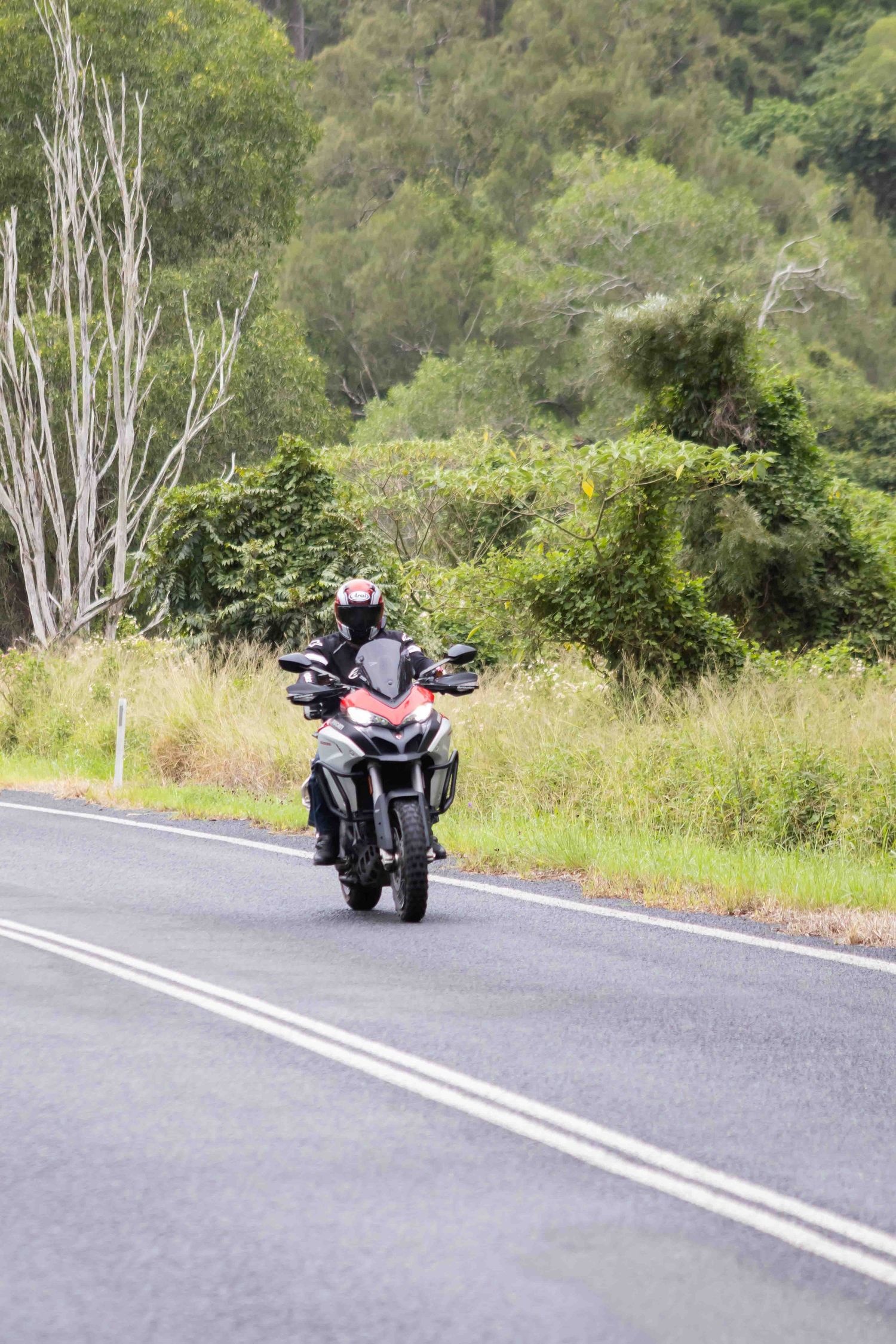 Motorcycles navigating a winding mountain road on a clear day.