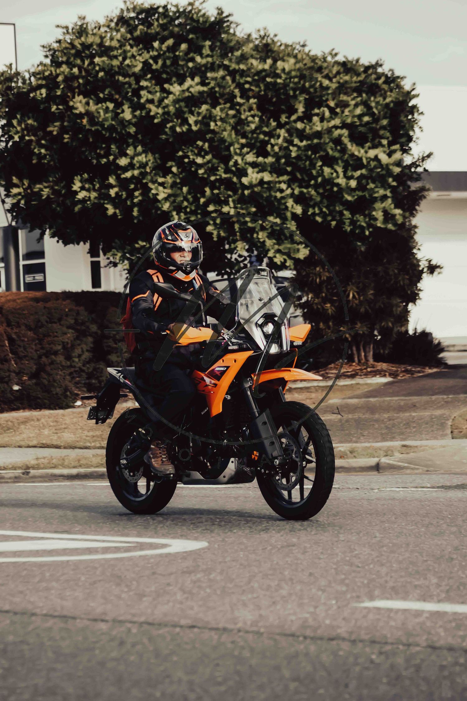 Rider on an orange KTM adventure motorcycle navigating a street corner, wearing full gear and helmet.