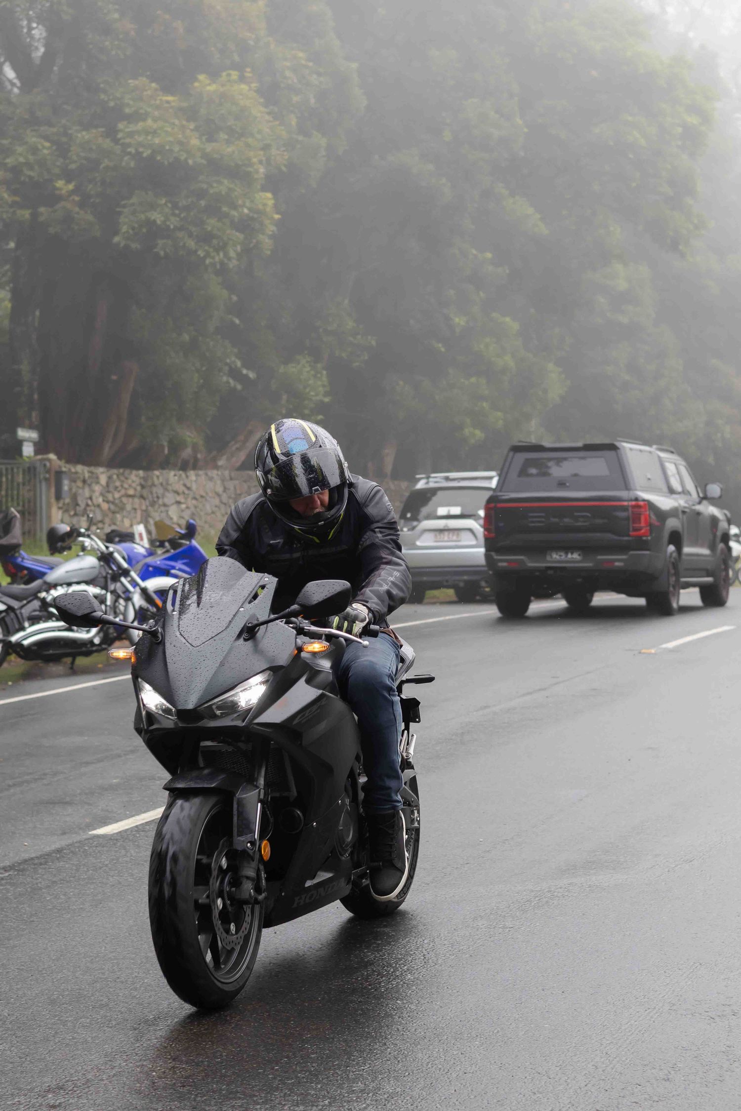Sport bikes lined up on wet asphalt during foggy weather conditions.