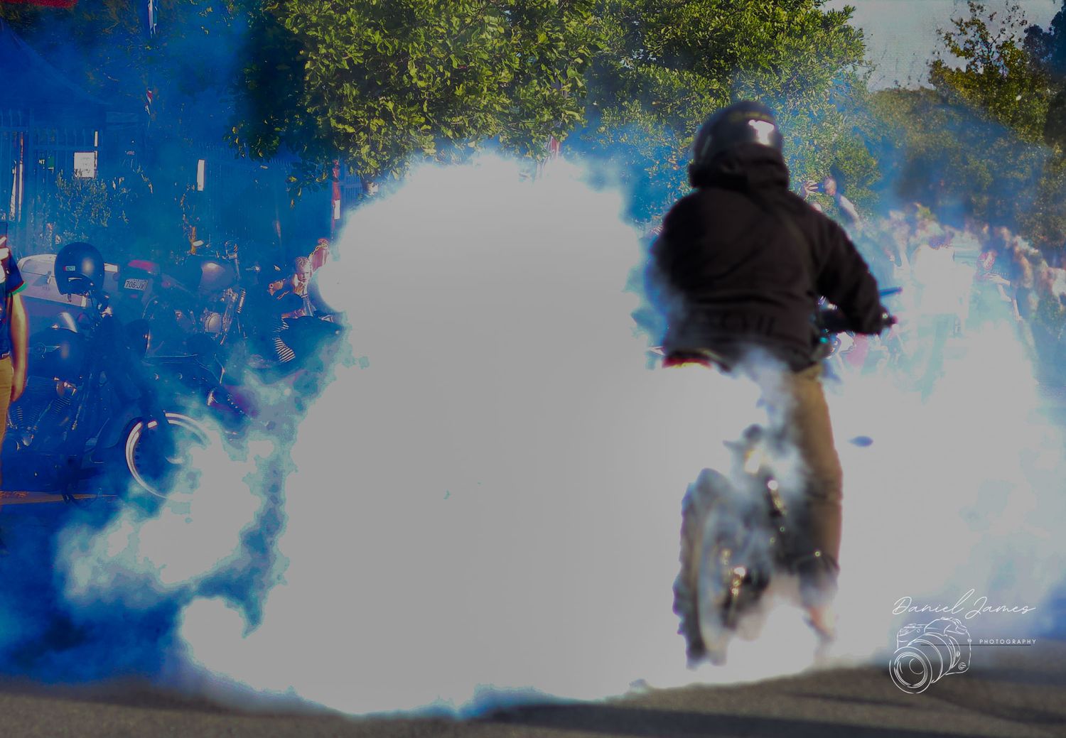 Motorcycle rider creating dramatic smoke trails during a burnout performance.