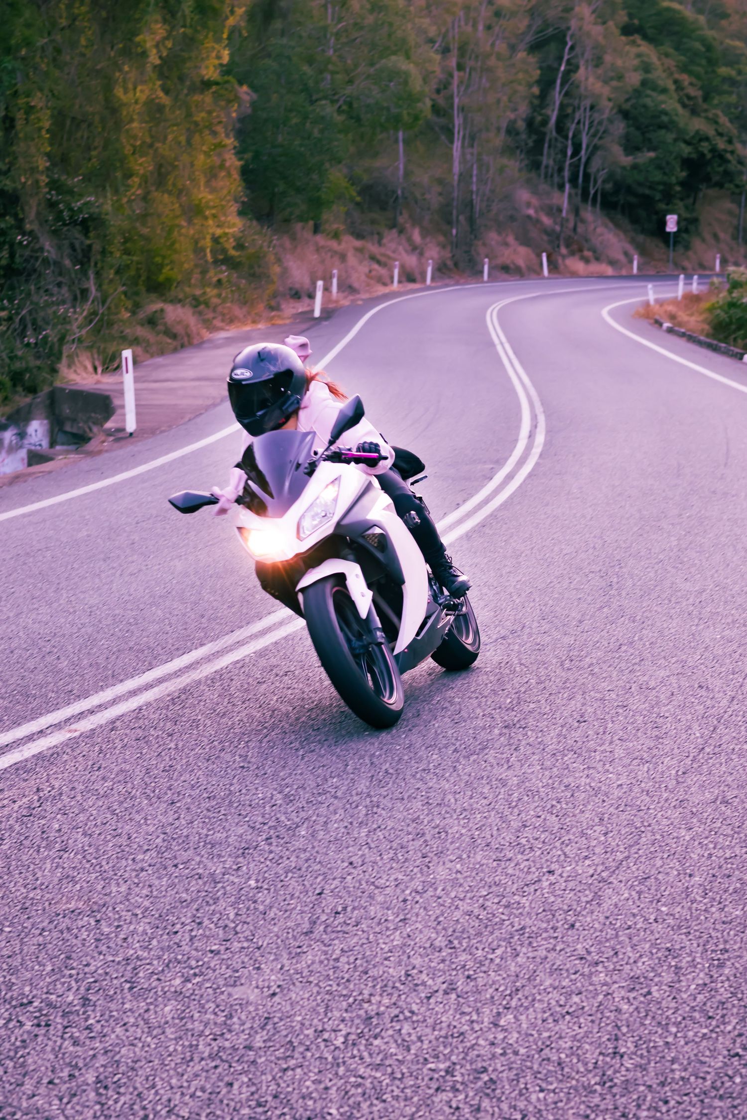 Motorcycle rider leaning into a curved mountain road with dramatic cornering angle.