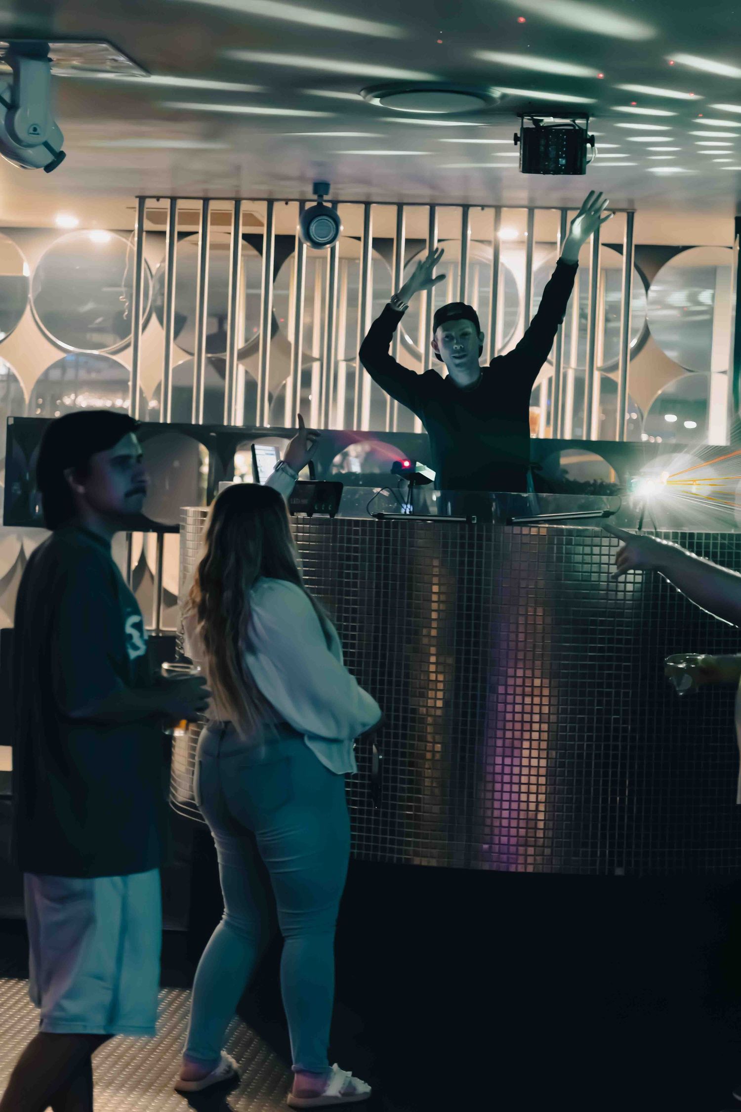 People dancing in a dimly lit nightclub with modern interior design and lighting effects.